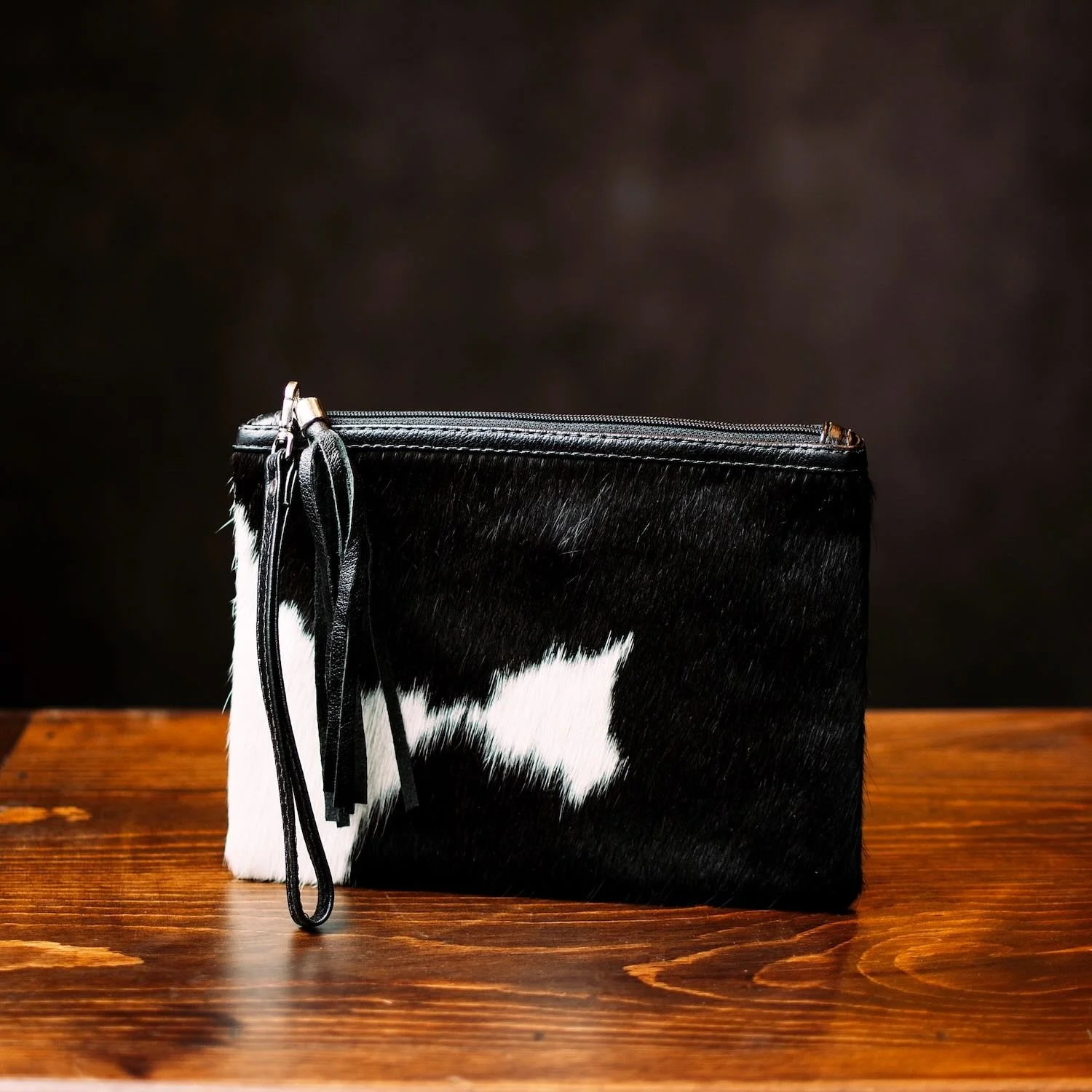 Handmade Brazilian cowhide clutch with fringe detailing, zipper closure, and wrist strap