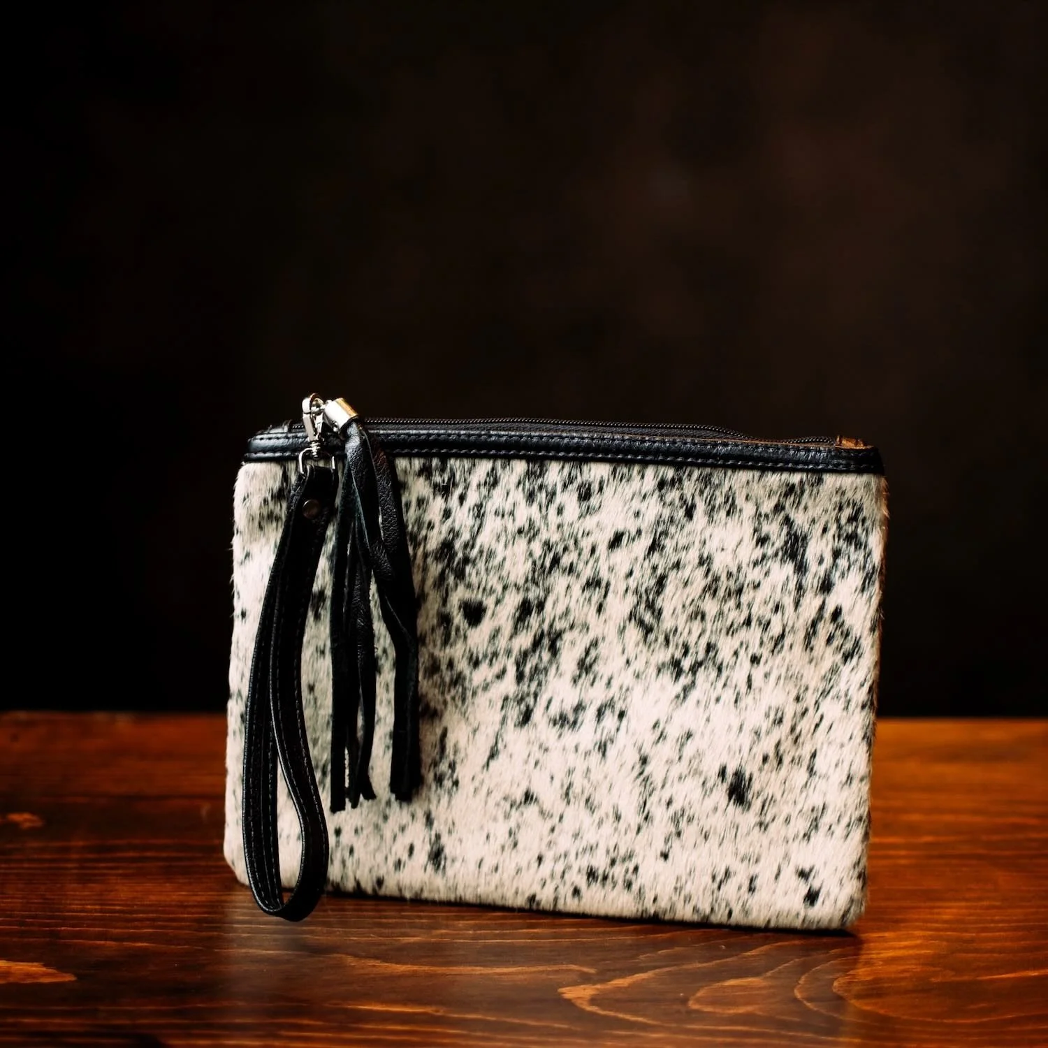 Handmade Brazilian cowhide clutch with fringe detailing, zipper closure, and wrist strap