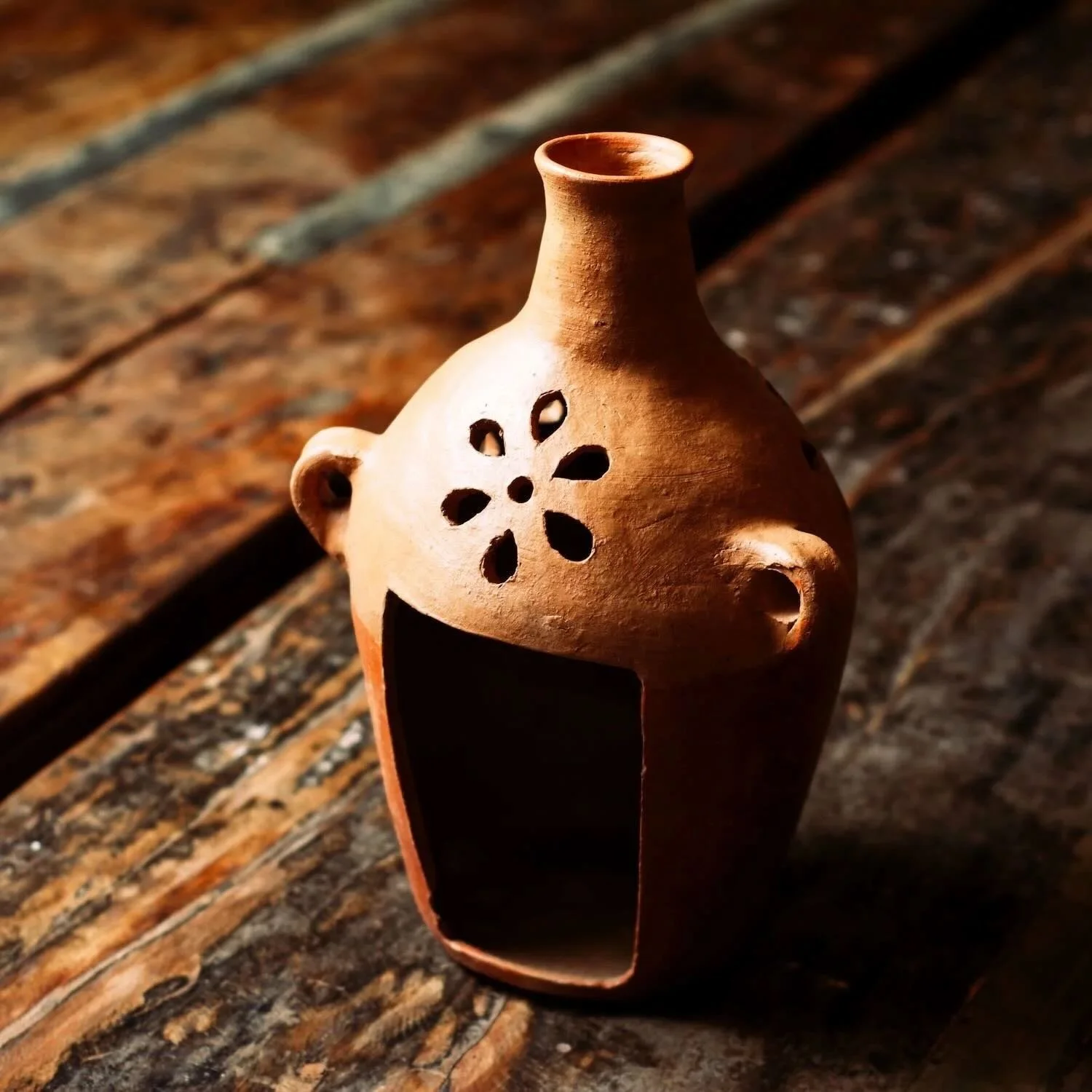 Shop a handmade terracotta jarra luminaria from Oaxaca, Mexico. Clay candle vase with cutouts for warm ambient lighting and rustic decor.