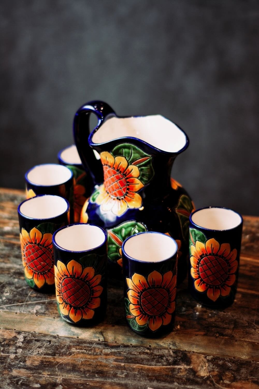 Talavera Sunflower Pitcher & Cup Set. Hand-painted Talavera set featuring a cobalt blue pitcher and matching cups with a vibrant sunflower design.