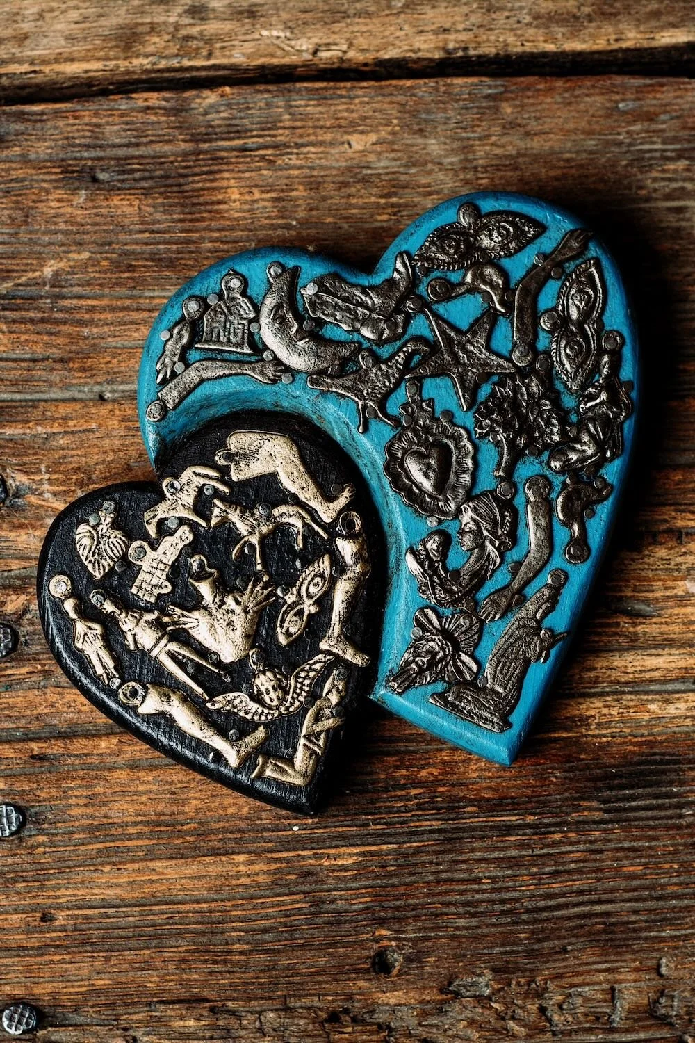 Shop Dos Corazones de Milagros handmade in Mexico. Blue and black folk art hearts with milagros charms and symbolic artisan wall décor.