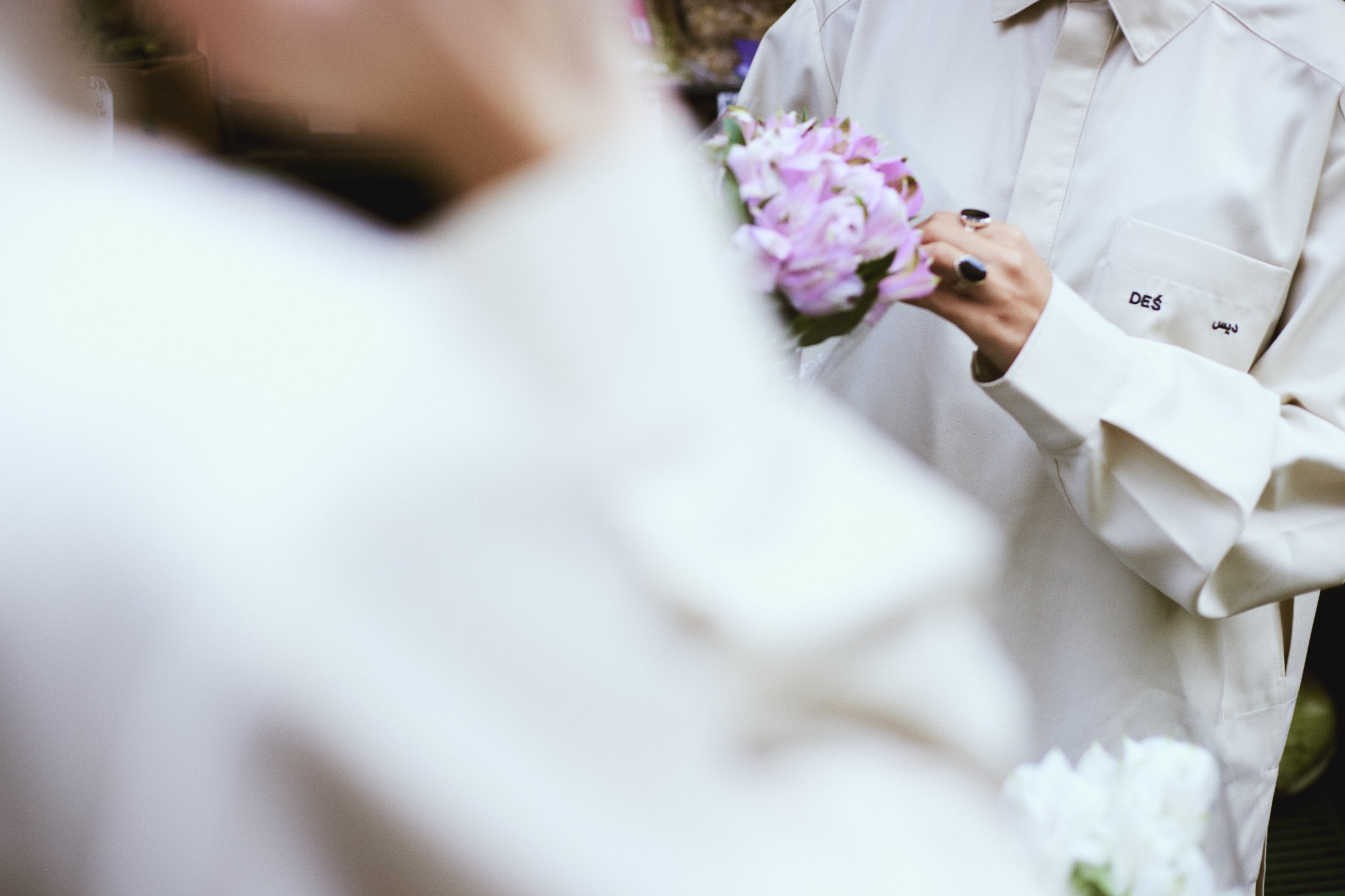 Person wearing a white shirt holding a bouquet of purple flowers.