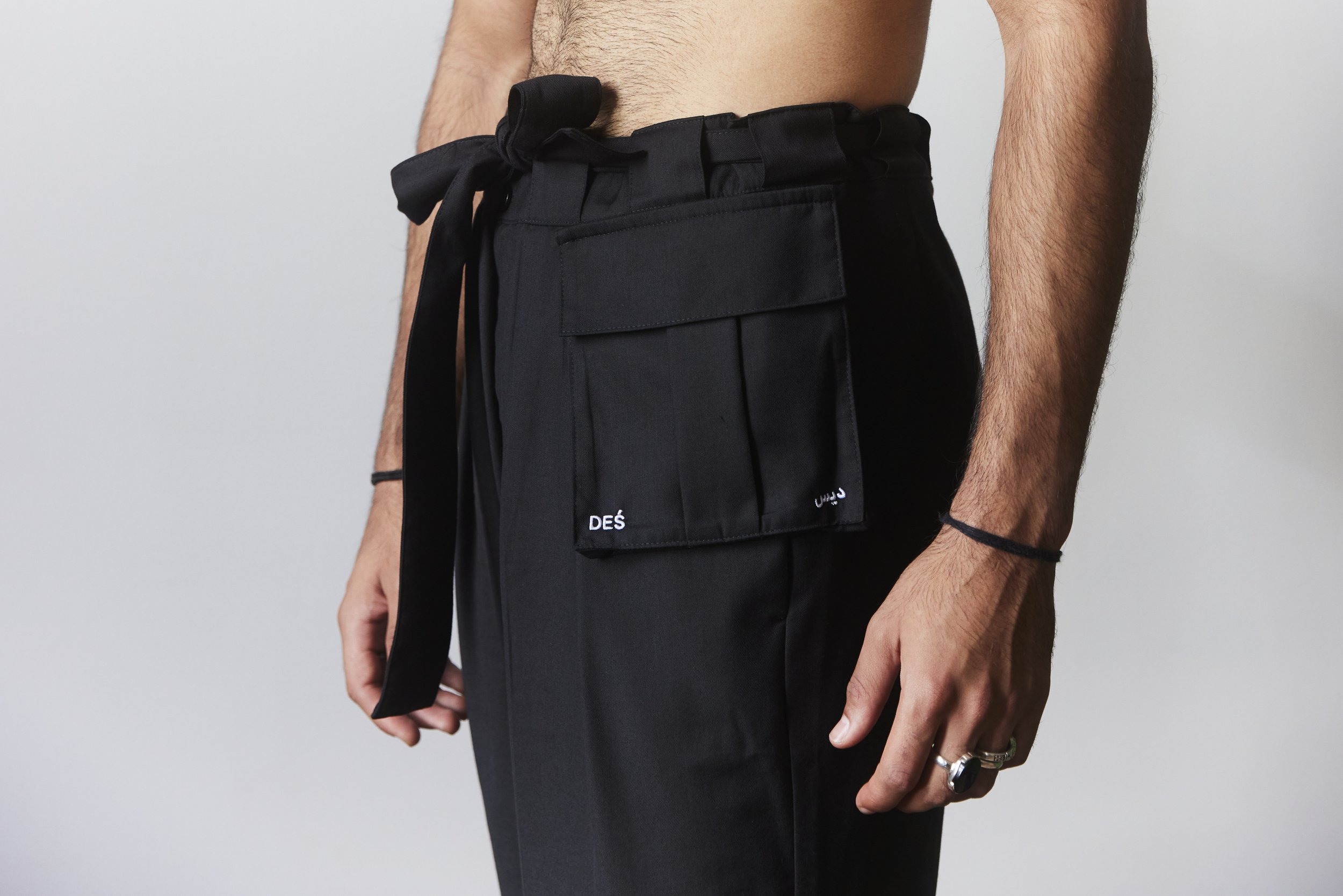 Person wearing black cargo pants with a tie waist and multiple pockets, showcasing a minimalist style.
