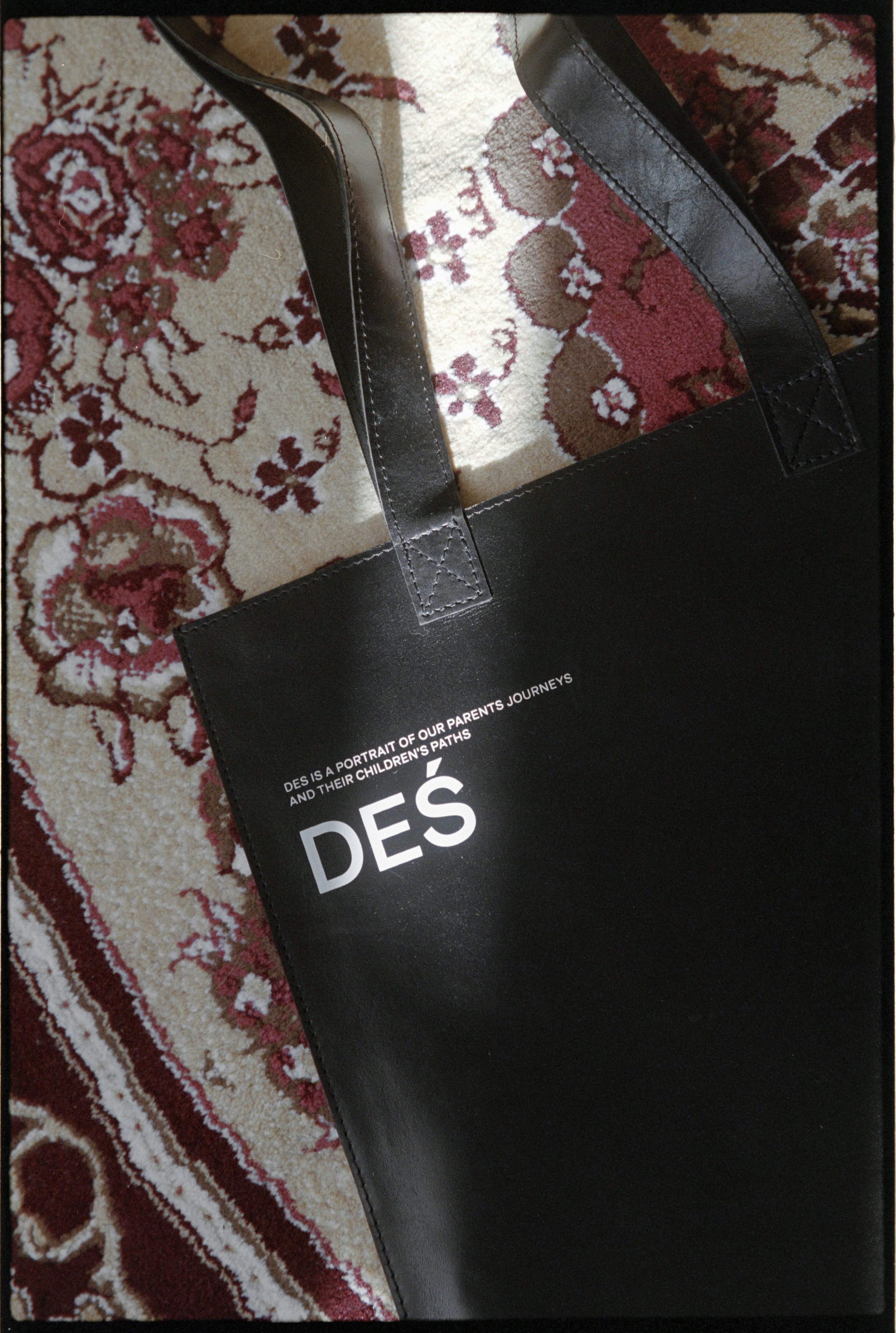 Black tote bag with white text on a patterned carpet.