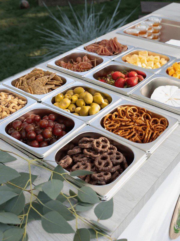 A charcuterie offering that includes colorful cherry tomato skewers, prosciutto, and cheese cubes on a wooden charcuterie cart.