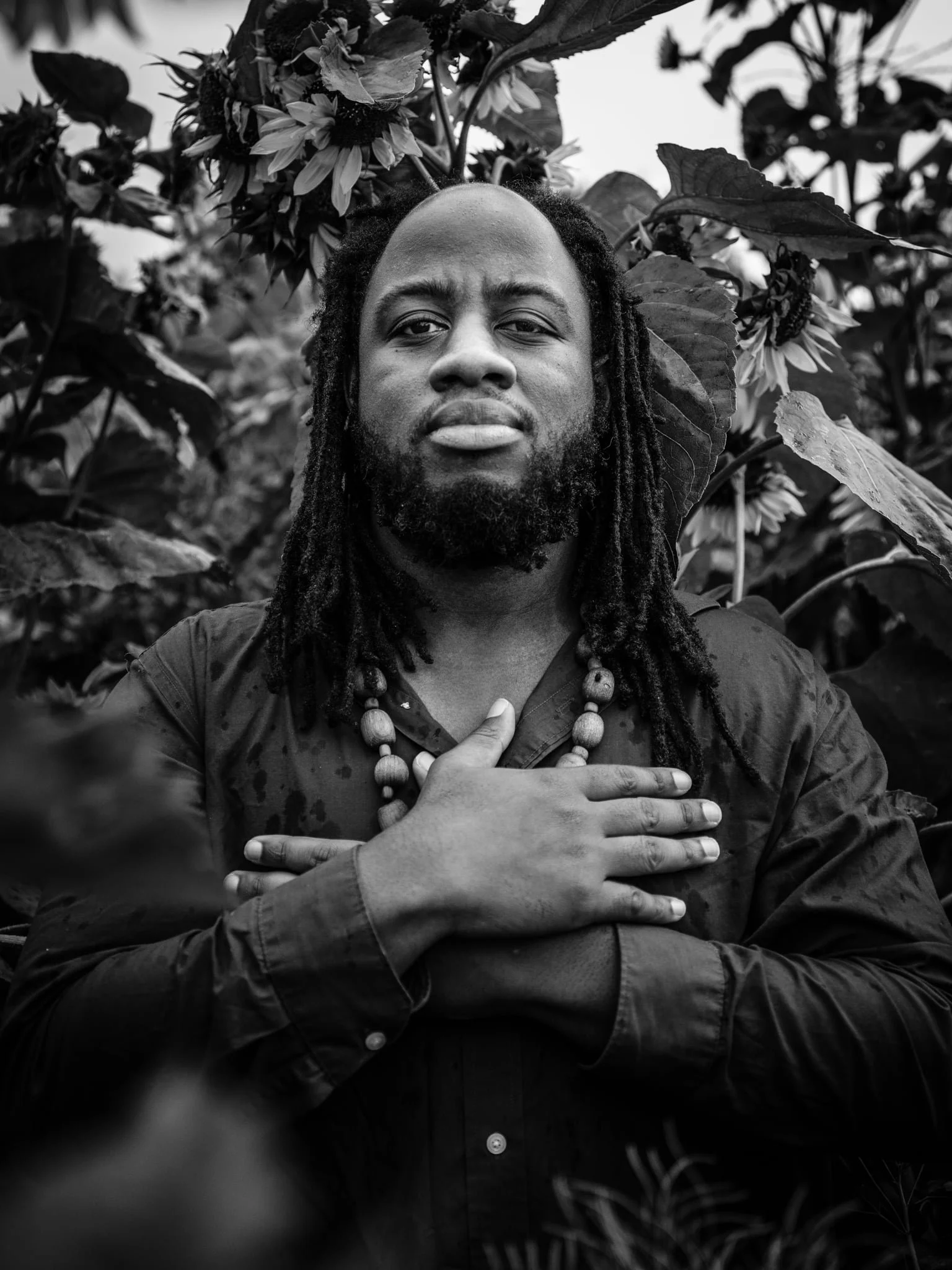 Man has hands crossed over his chest. He has long braided hair, and a beard.