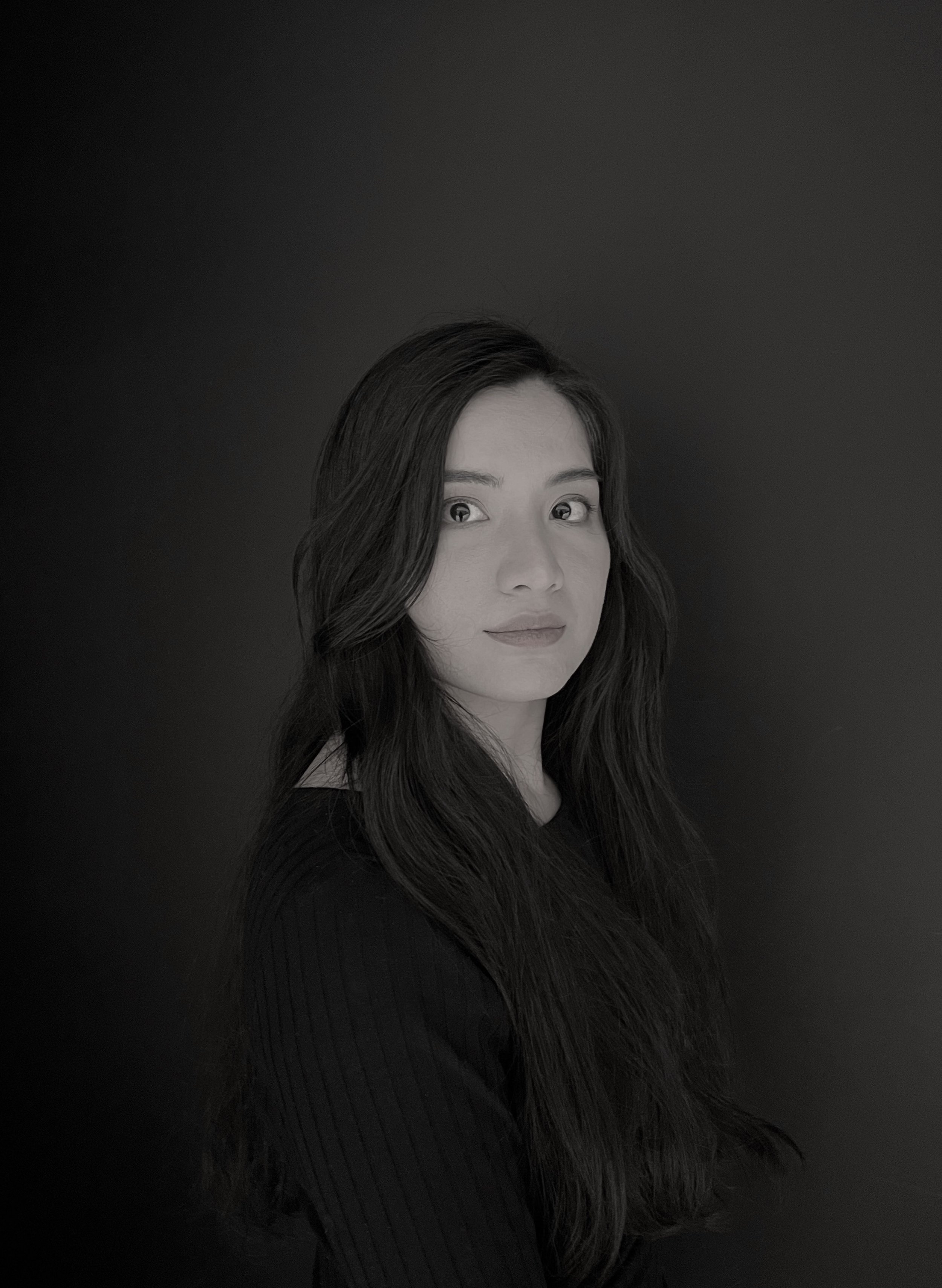 Woman looking at camera. She has black hair and a black shirt