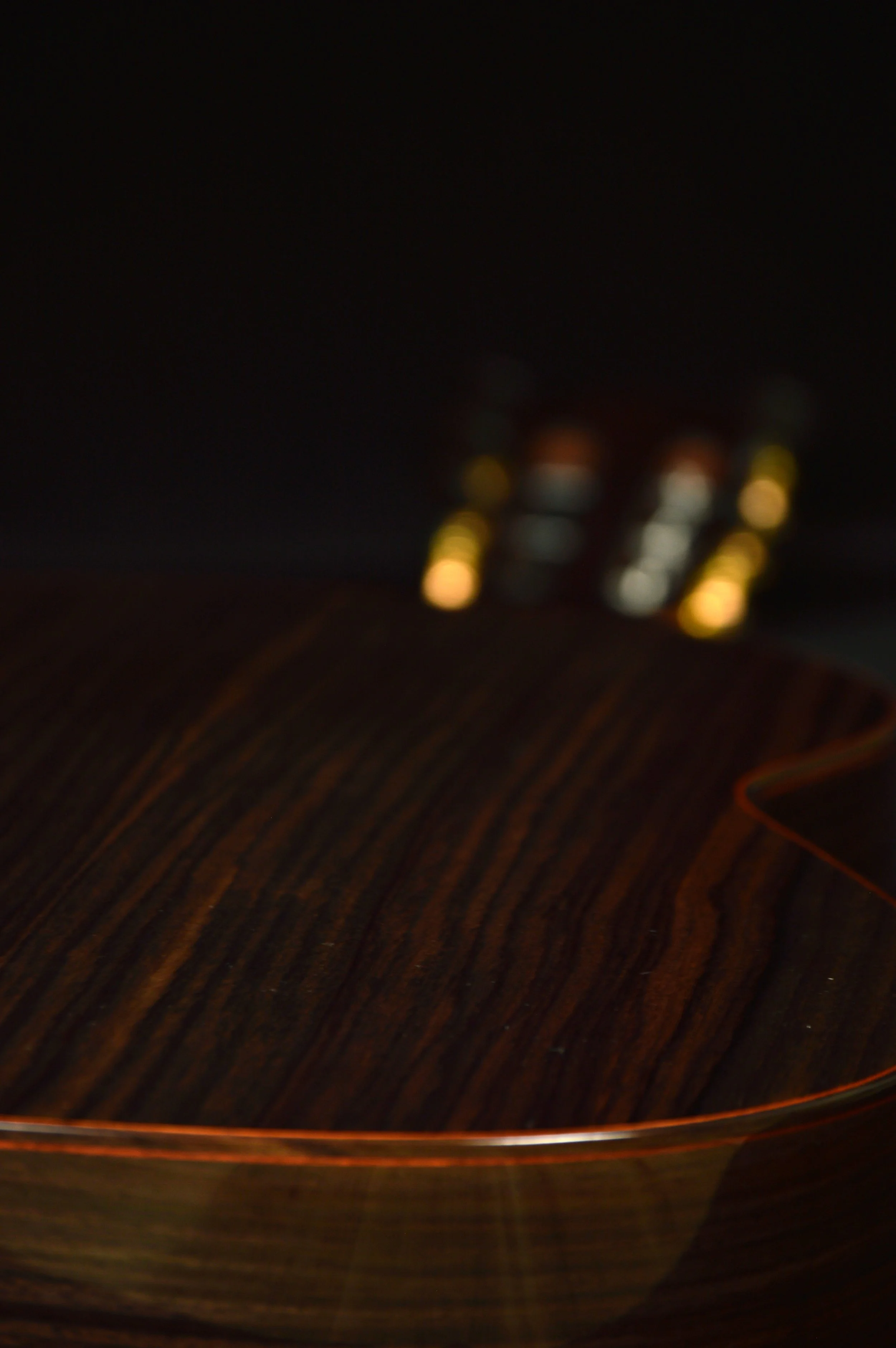 Cole up of the rosewood and bloodwood binding on a classical guitar on a black backkground