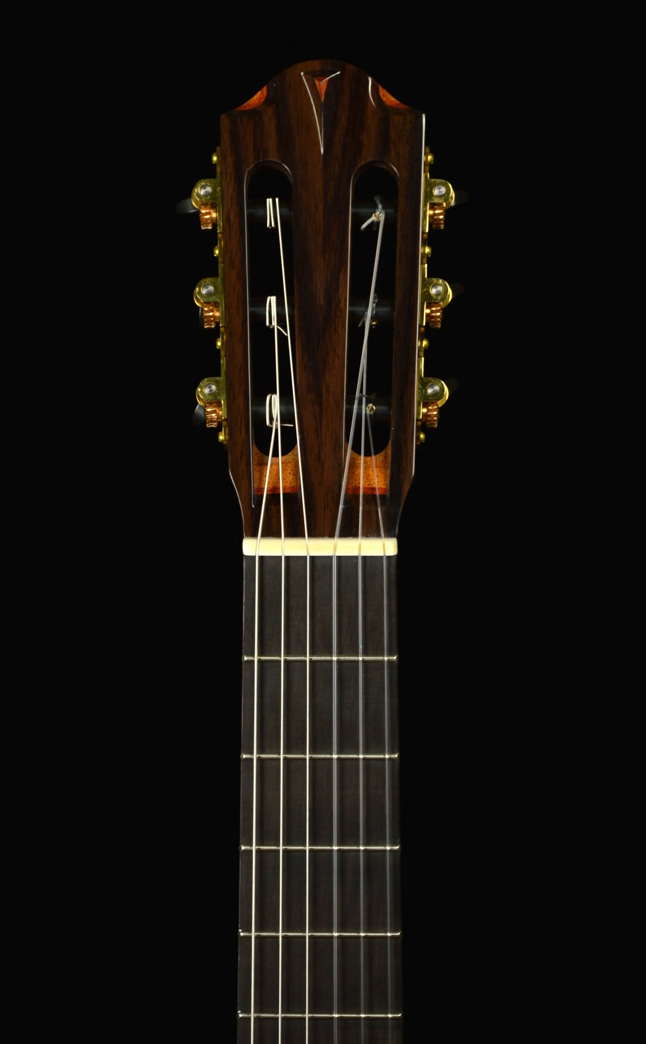 Close up of the headstock on a Classical guitar with cedar top on black background