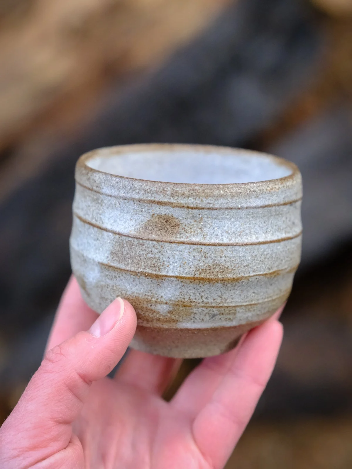Organic handmade cup held in hand, featuring the balanced shape and size.