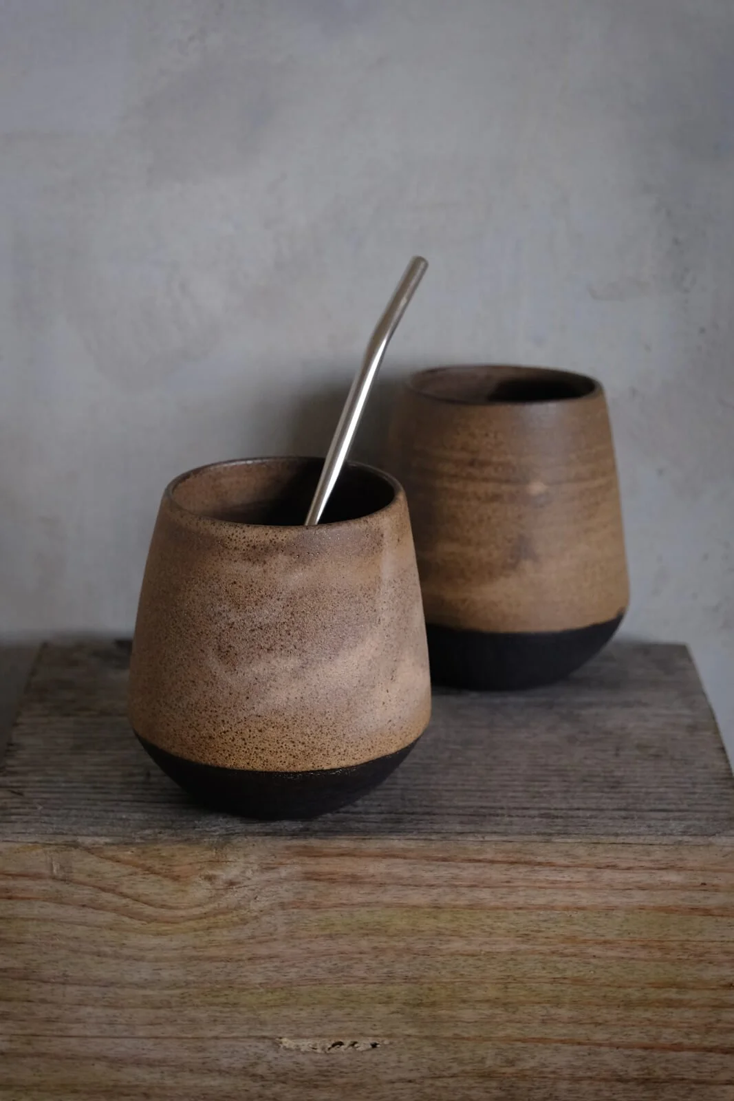 Yerba mate cups in black textured clay and sandstone natural beige finish in minimalist setting.