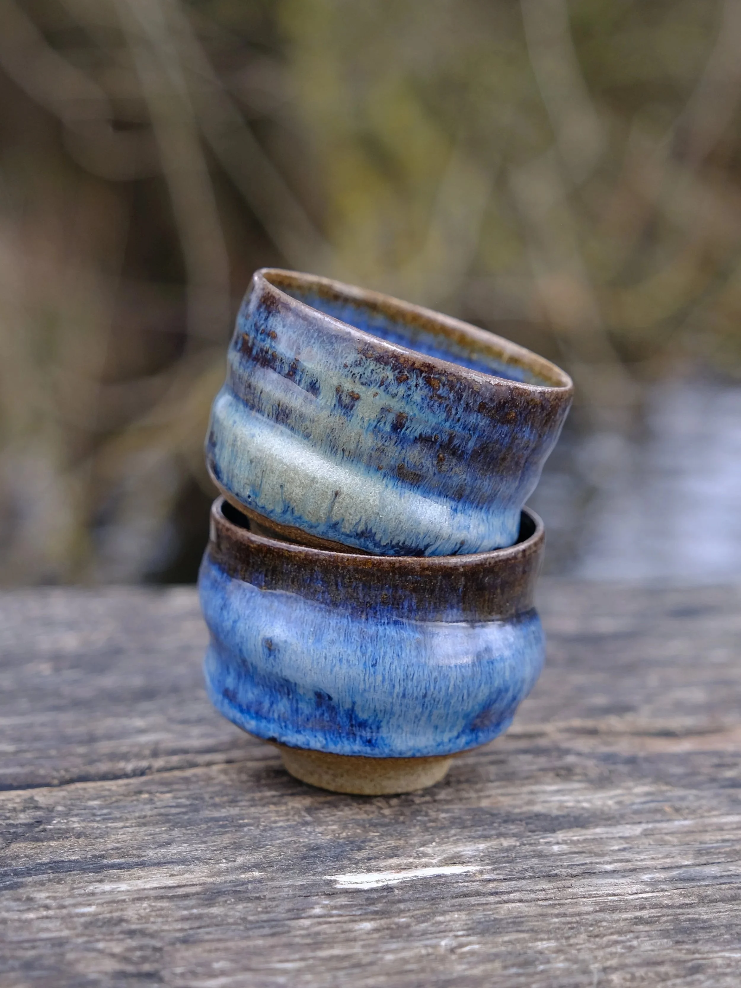 Handmade ceramic cups with earthy base and flowing blue finish.