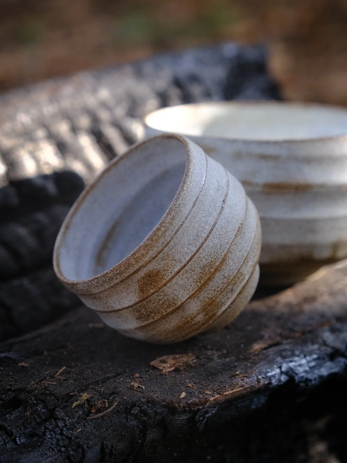 A close-up of a cup and a chawan showing the swirly lines and stone-like glaze effects.