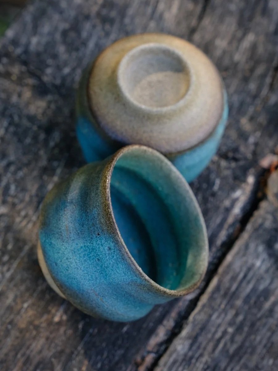 A pair of natural opaque emerald-blue cups featuring weavy organic form.