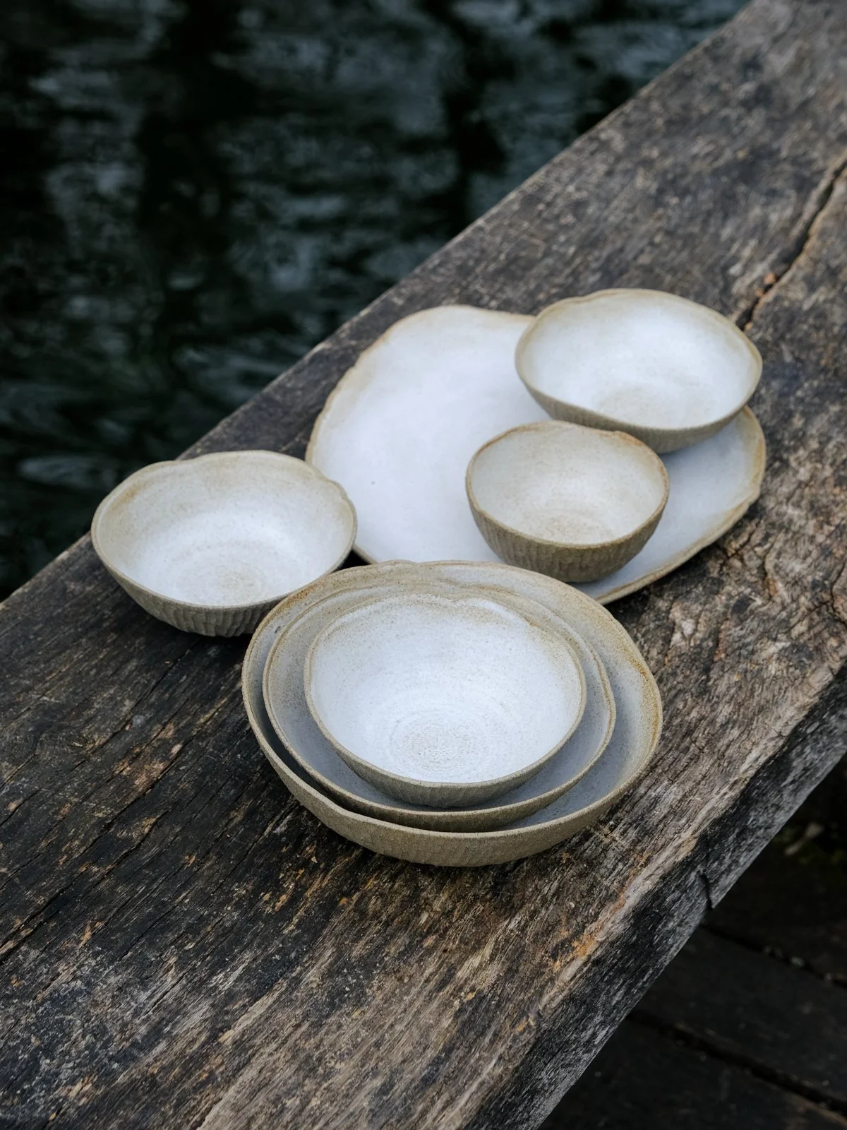 Dinnerware collection of plates and bowls in different sizes, textured stone exterior and off-white rustic finish.
