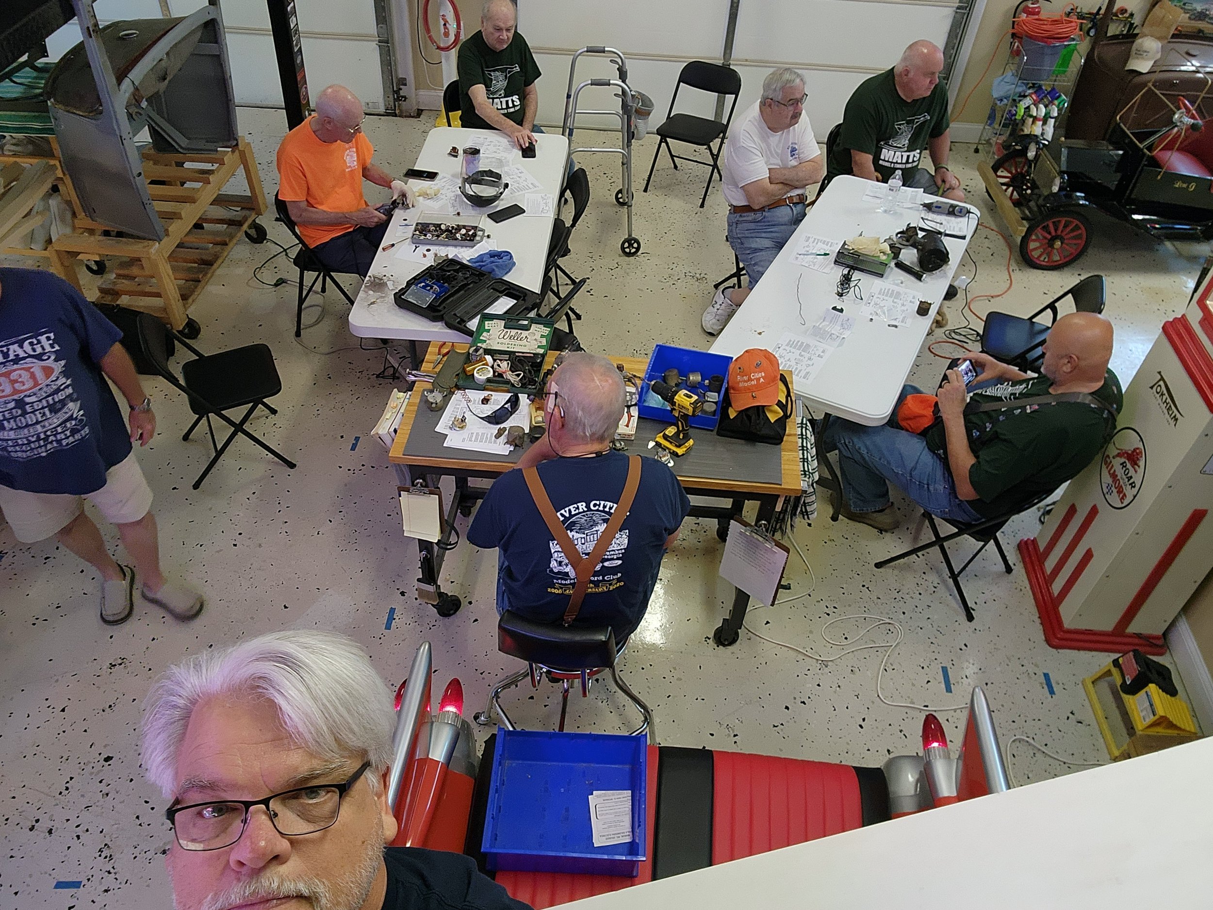 Group of people working at a hobby workshop with tables, tools, and vintage decor