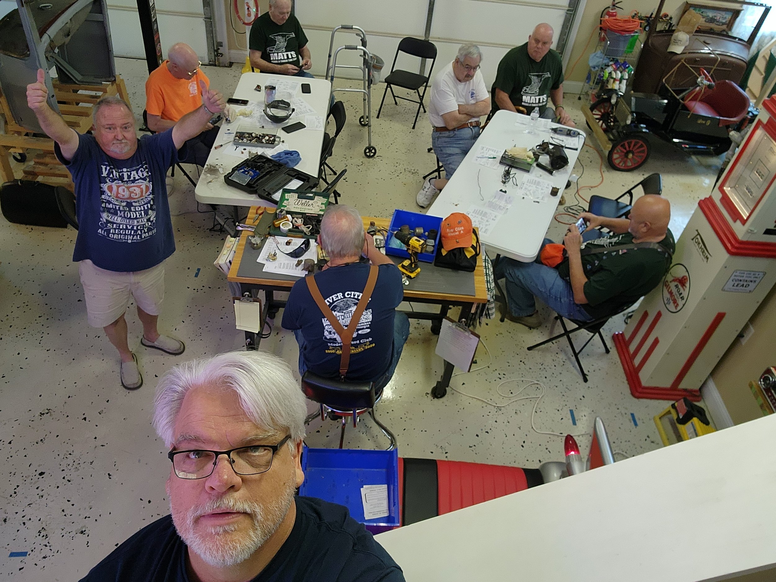 Group of men at a workshop with tools and vintage car in garage