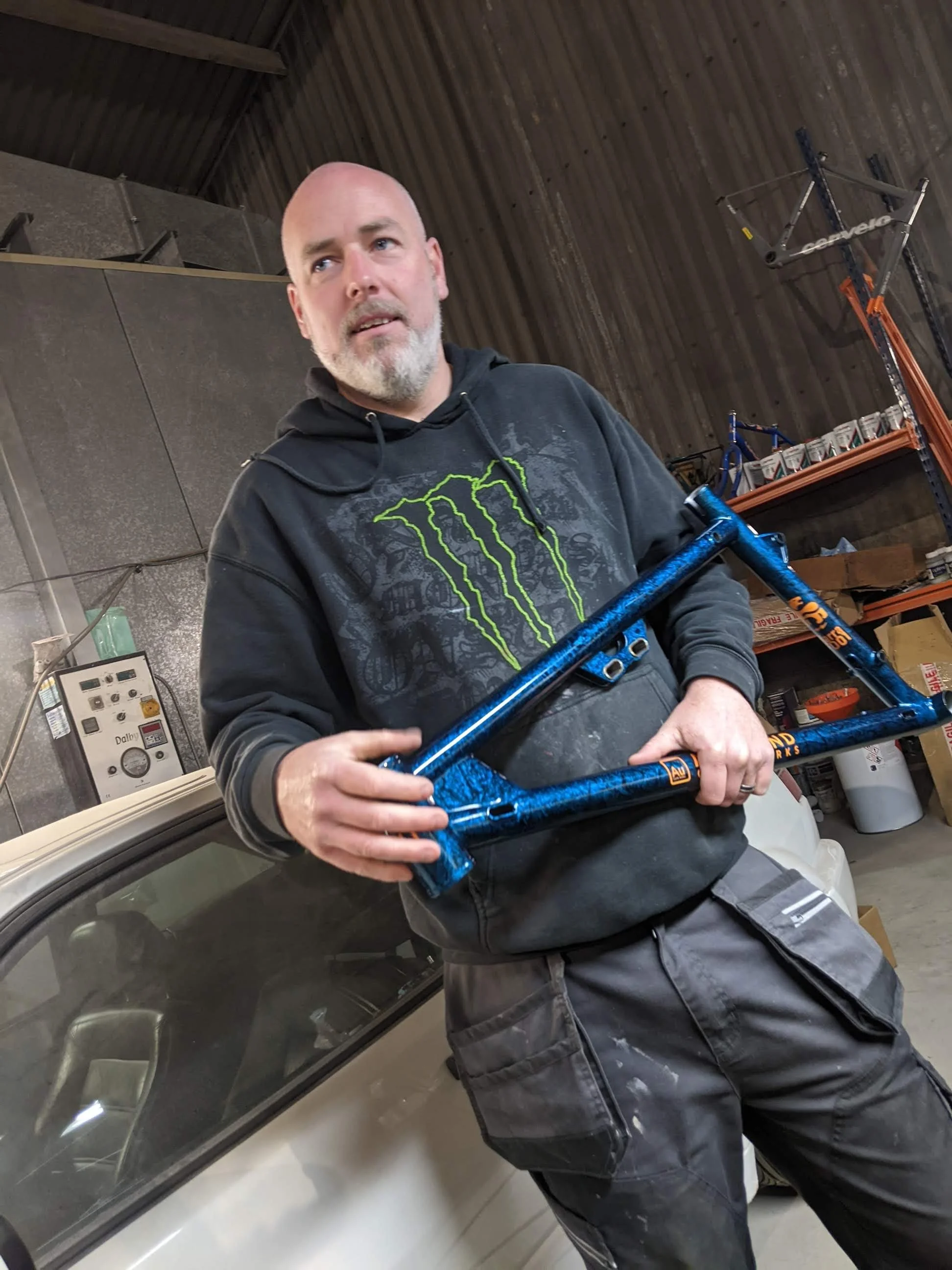 Stu @ Black Cat Custom Paint, holding a beautifully painted Auckland Cycle Works Marra front triangle.
