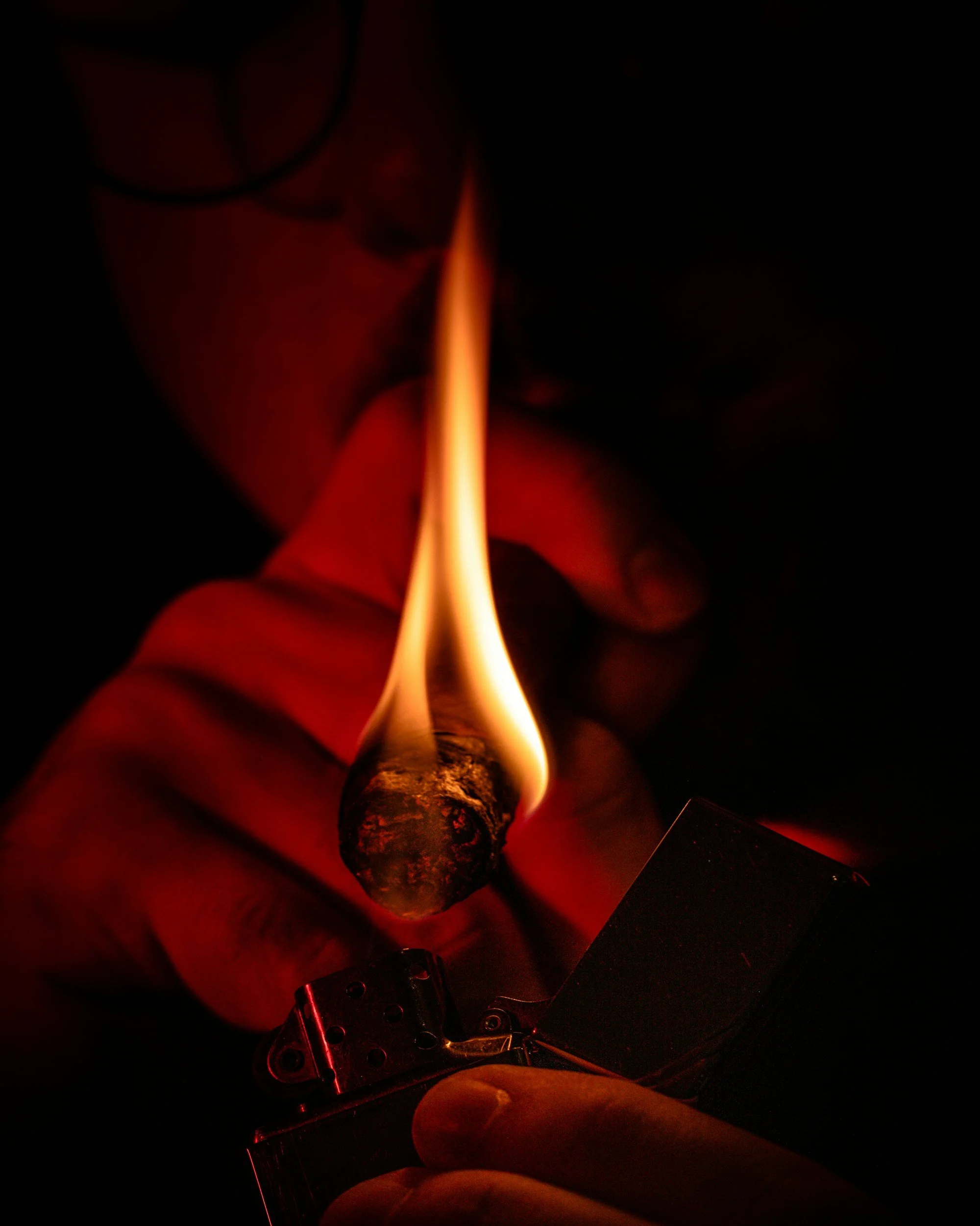 A close-up of a matchstick igniting, with a flame at the tip, in a dark environment illuminated by the flame.