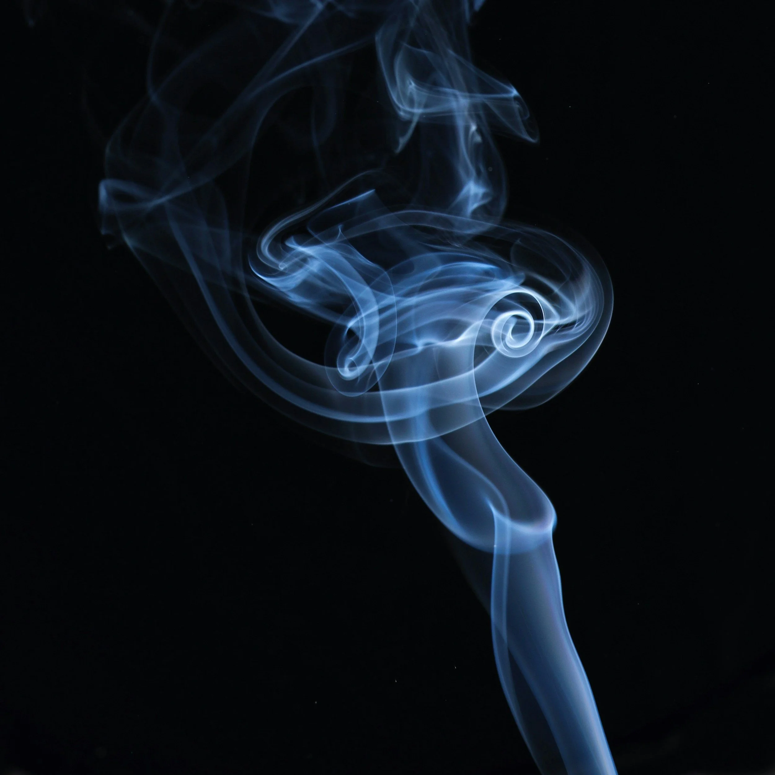 Close-up of blue and white smoke swirling against a black background.