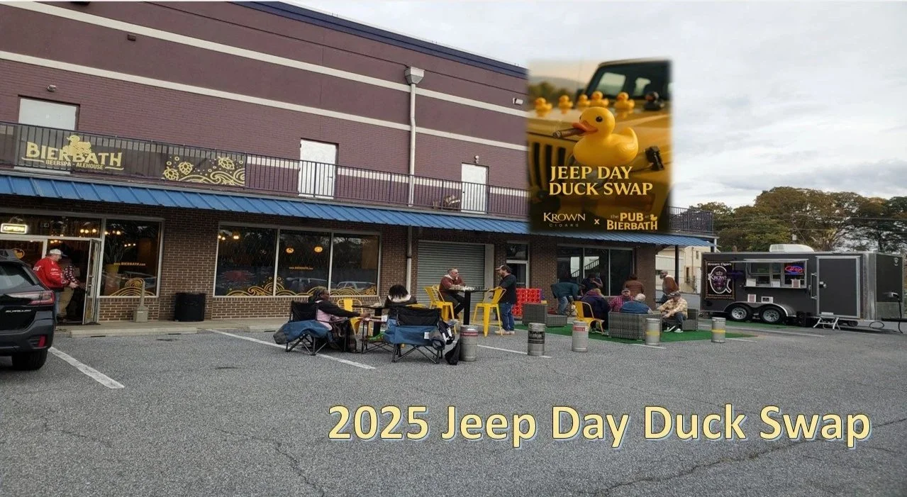 A parking lot outside a building with people gathered around tables and chairs. A trailer is parked on the right side. A large poster advertises the 2025 Jeep Day Duck Swap event, featuring rubber ducks and a Jeep vehicle. Text on the image is '2025 Jeep Day Duck Swap' and 'JEEP DAY DUCK SWAP'.
