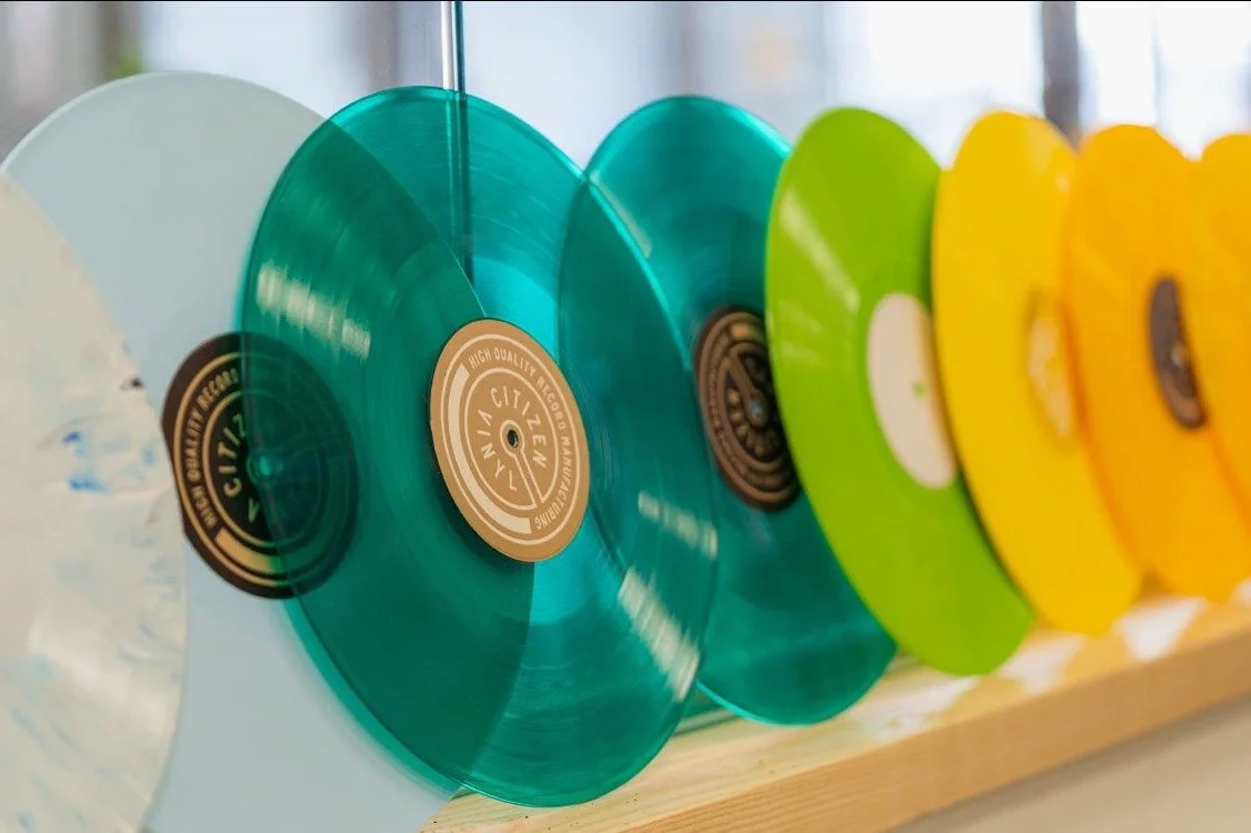 a row of vinyl LPs in shades of green and yellow.