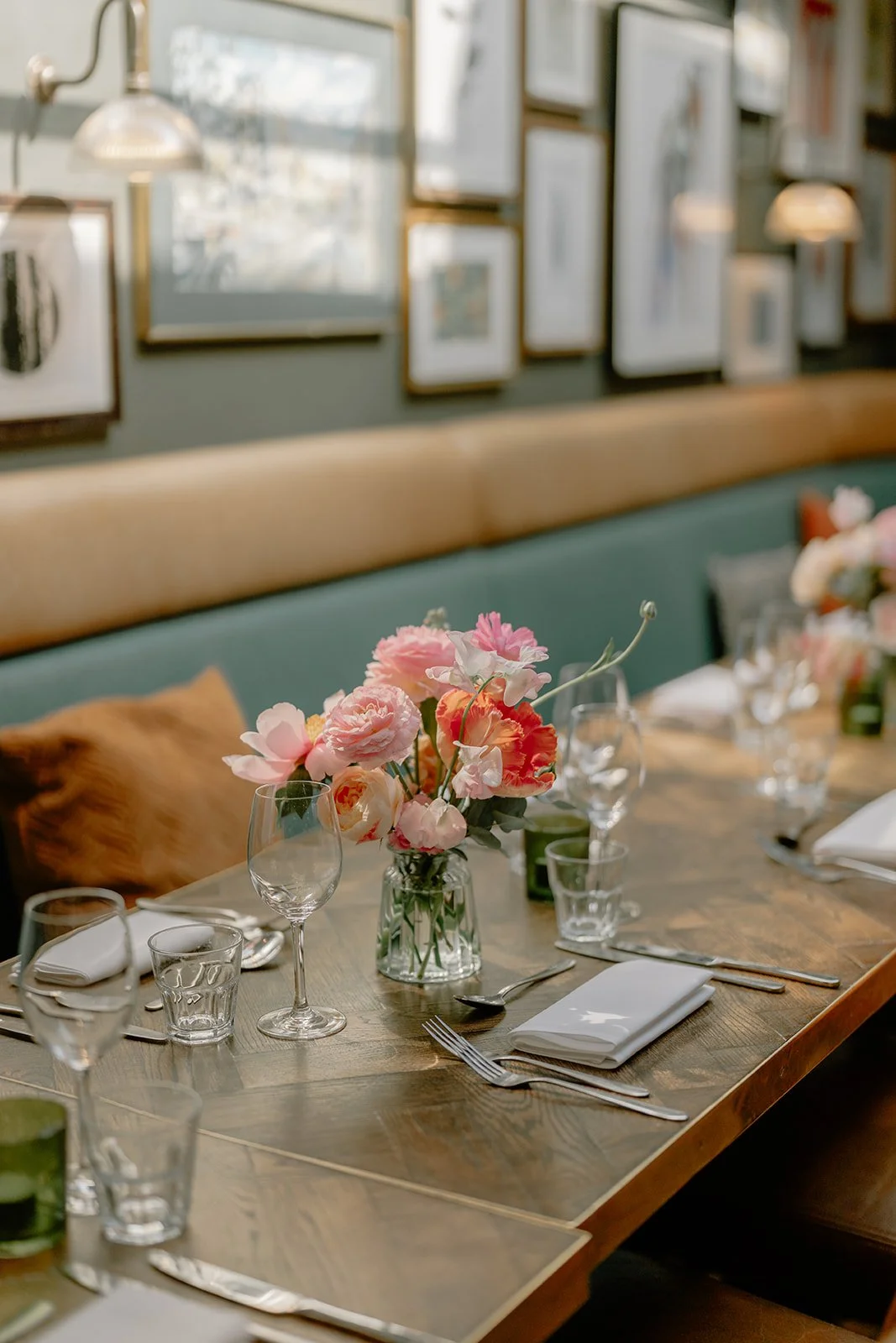 A table set for a meal with a floral centerpiece, wine glasses, and cutlery in a decorated dining area.
