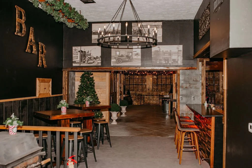 Festive restaurant interior with a decorated Christmas tree, wooden tables, bar seating, and holiday decorations.