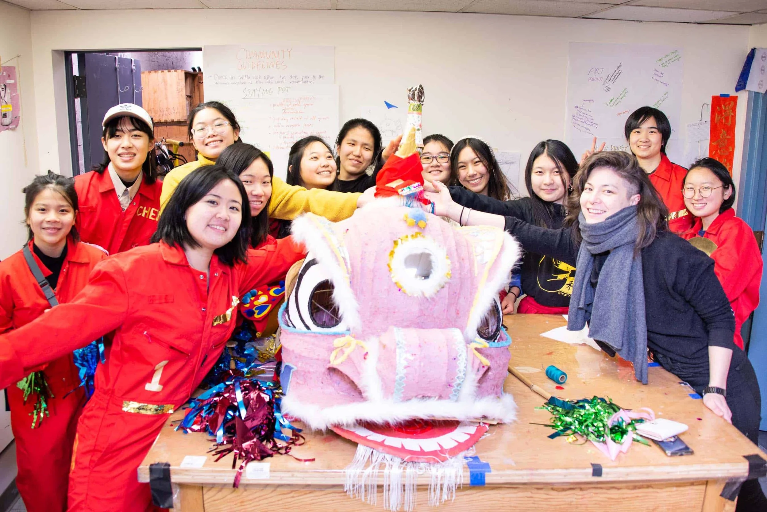 Group of young women around a table celebrating a Chinese dragon or lion dance costume.