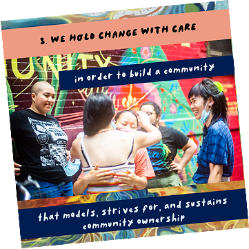 Group of people in front of a colorful mural, engaging in conversation, with a woman wearing a face mask and others smiling.