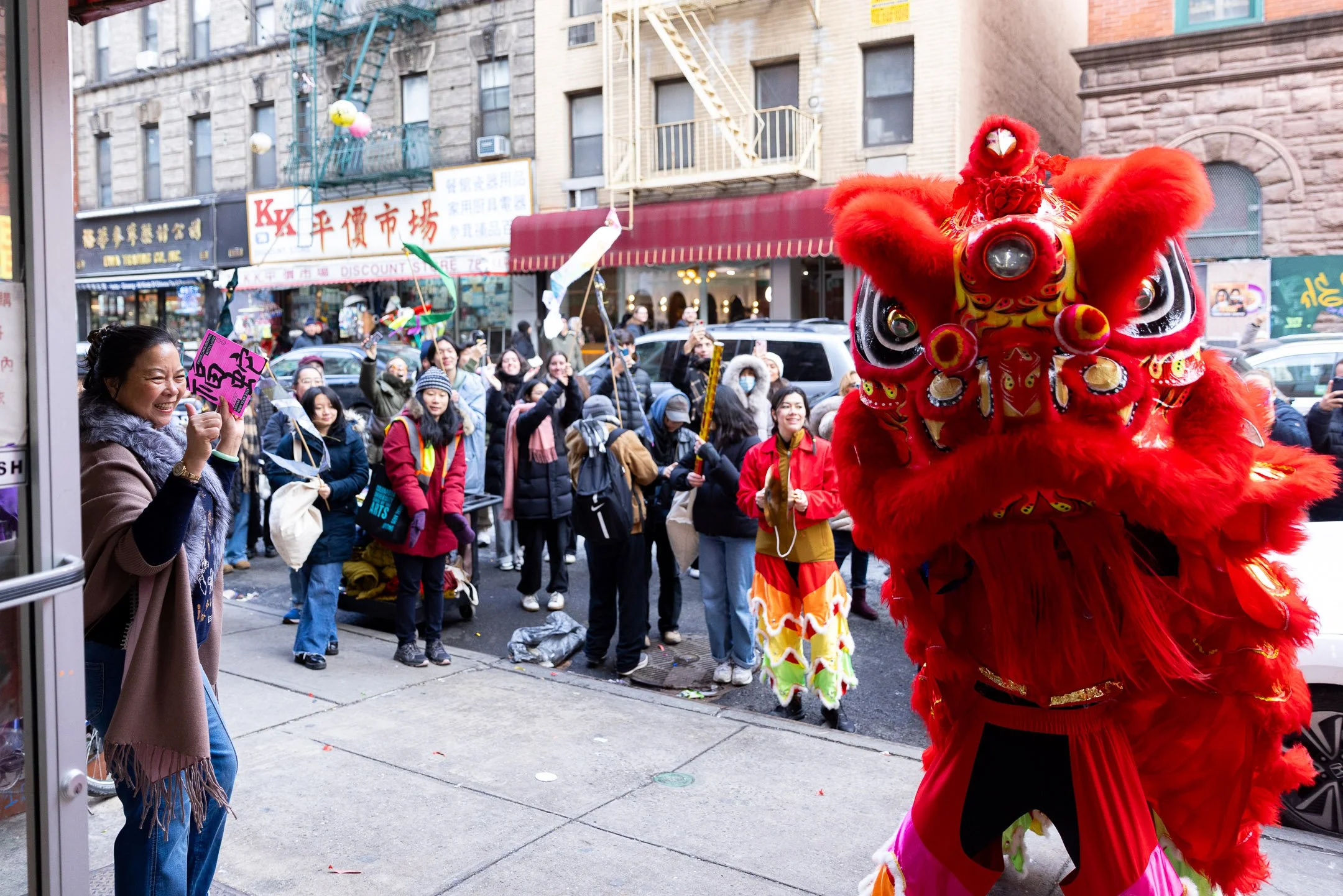 People watching a traditional Chinese lion dance performance on a city street during a celebration.