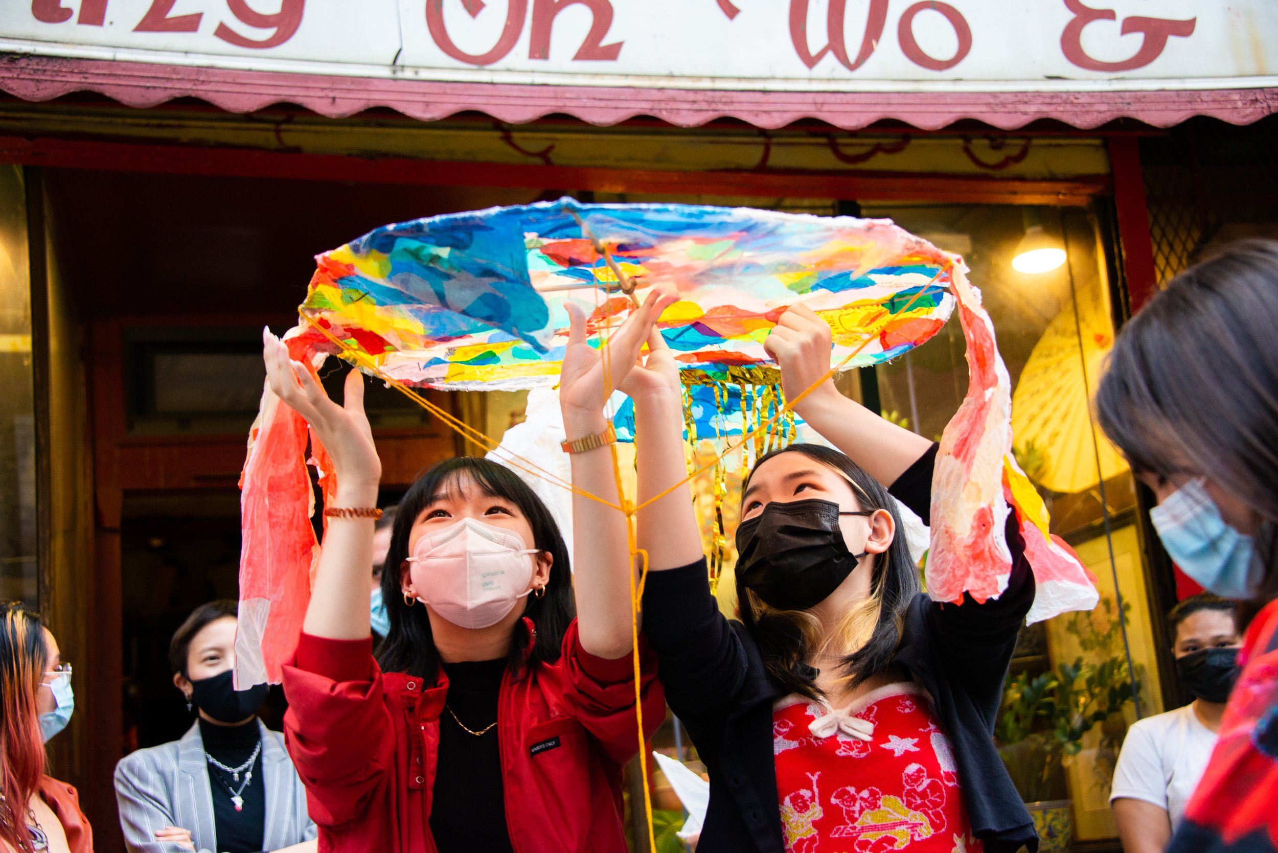 Two women wearing face masks holding paper lanterns during a celebration or festival.