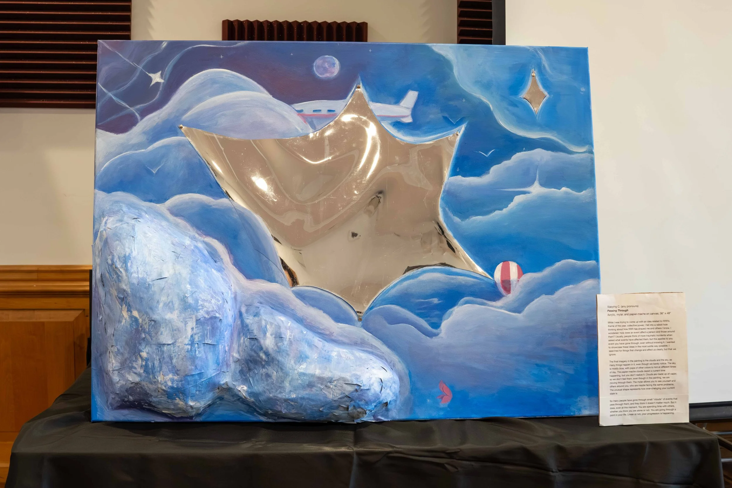 A mixed media painting titled 'Passing Through' on canvas, depicting a scene with blue clouds, a starry night sky, a moon, and a spacecraft flying through the clouds, with a small red figure at the bottom.