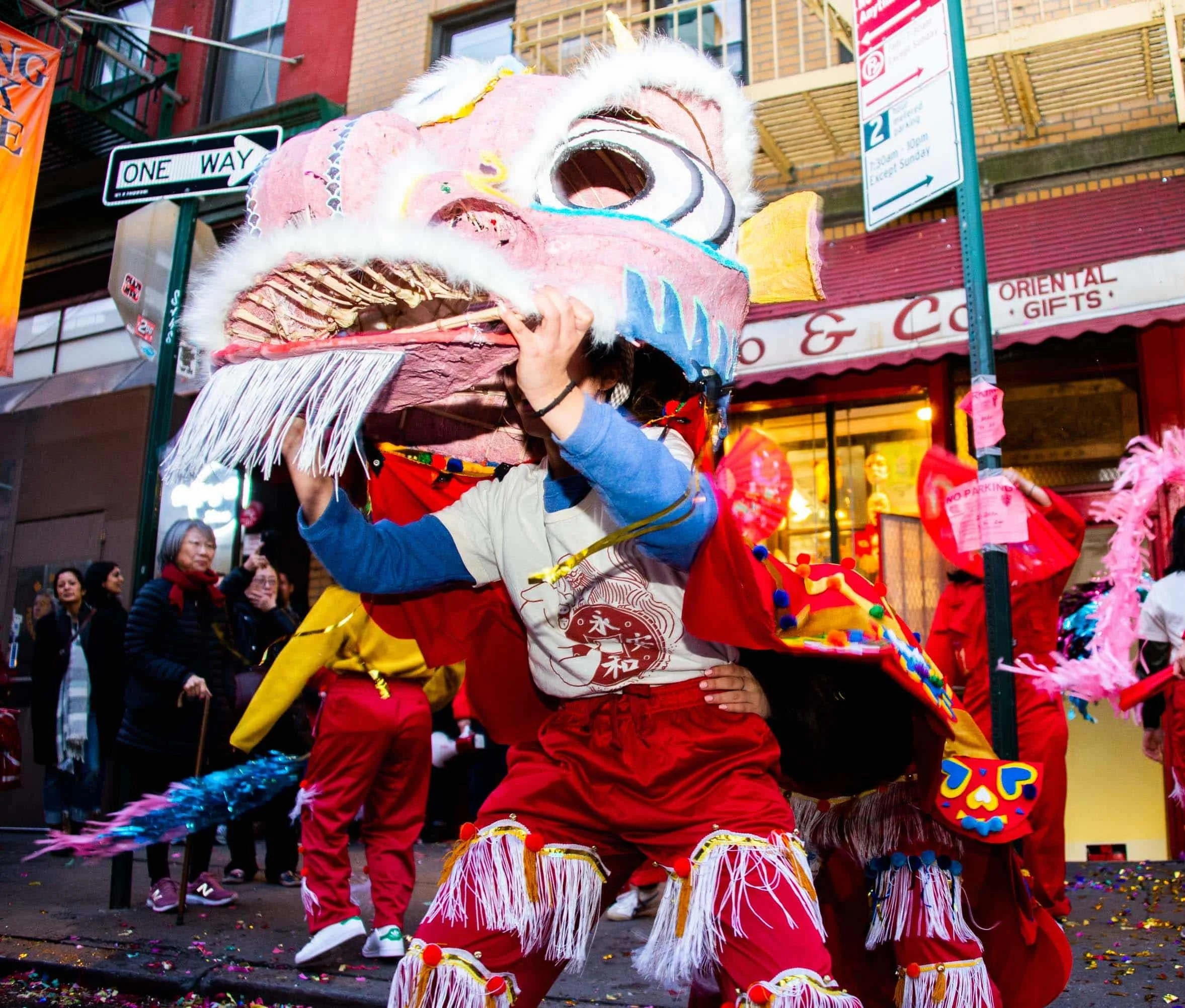 People participating in a dragon dance parade during a street celebration, with onlookers watching.
