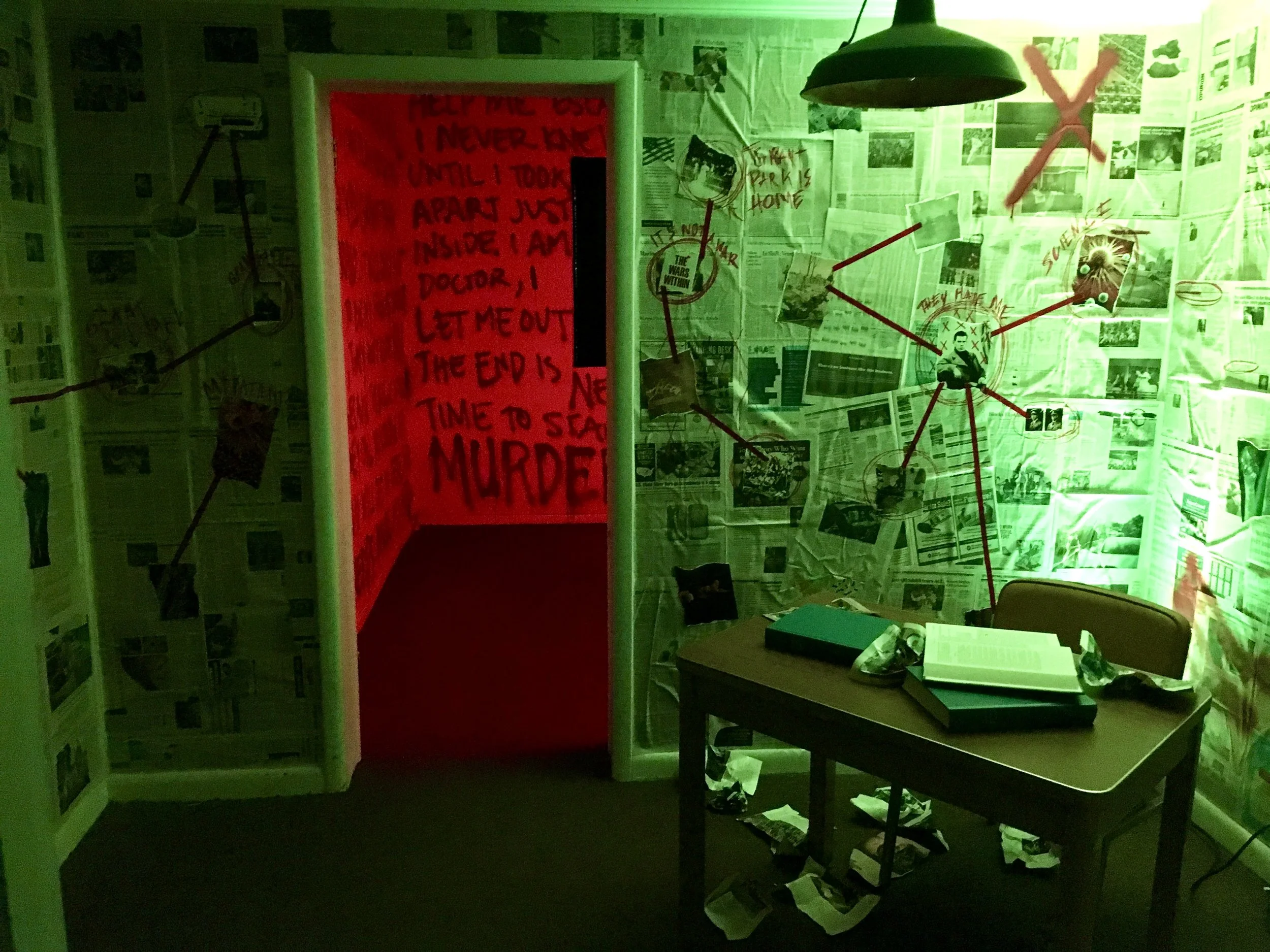 A dimly lit room covered in newspaper clippings with red string connected to various clippings, suggesting a conspiracy board. A red lit doorway with ominous writing on the walls. A table with books and papers strewn about. A red 'X' is marked on the wall.