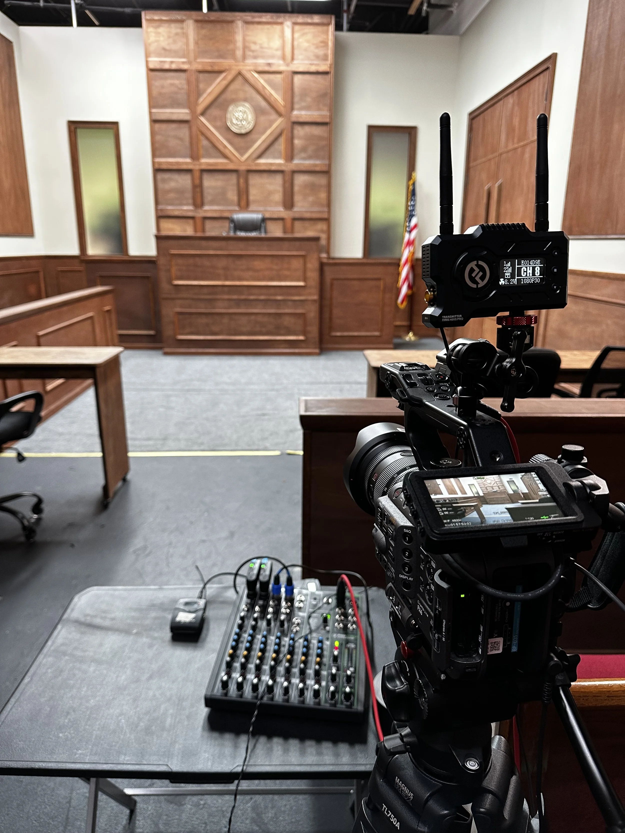 Film set resembling a courtroom with a judge's bench and camera equipment.