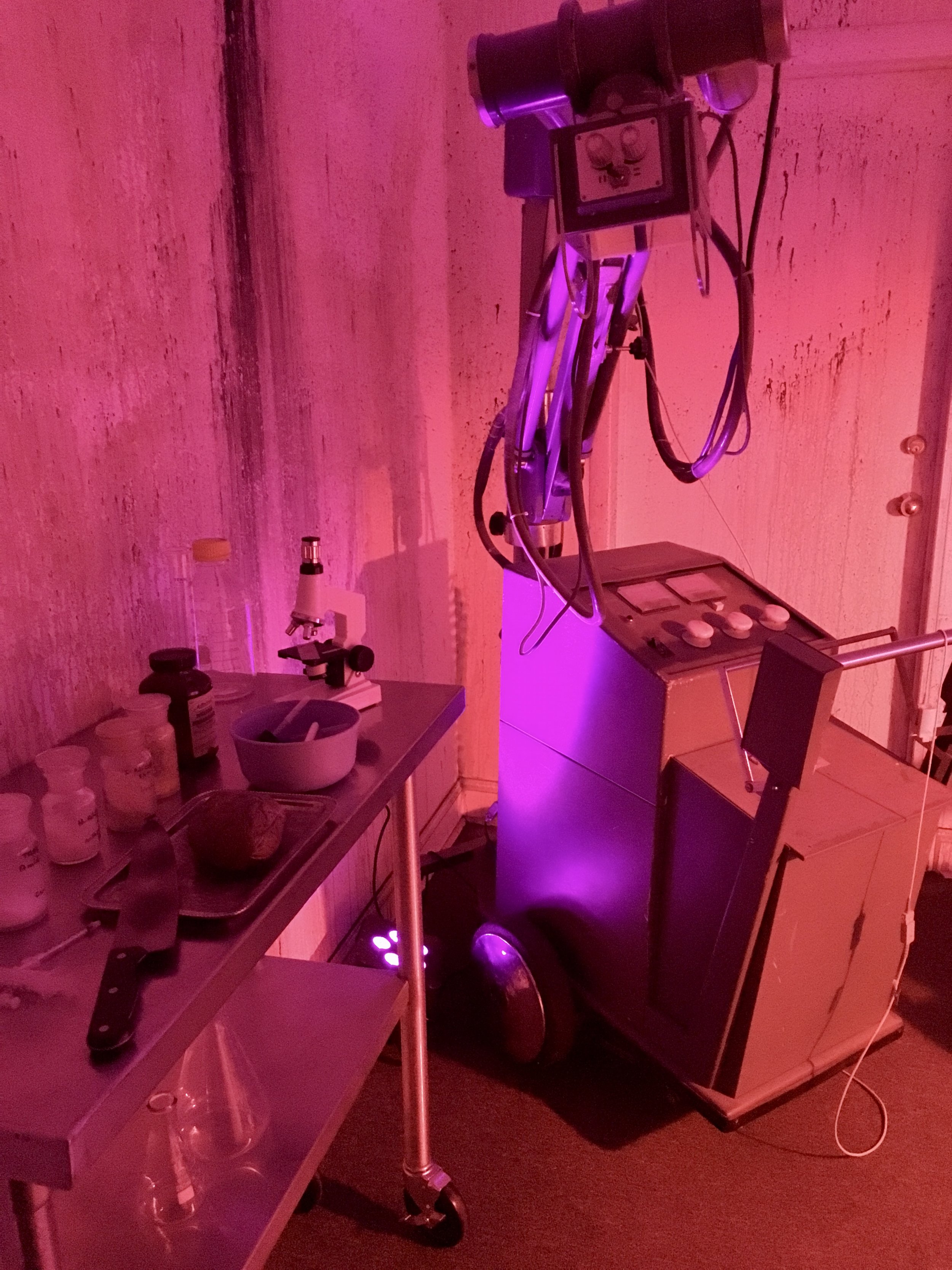 Vintage X-ray machine and lab cart with bottles, microscope, knife, and bowl.