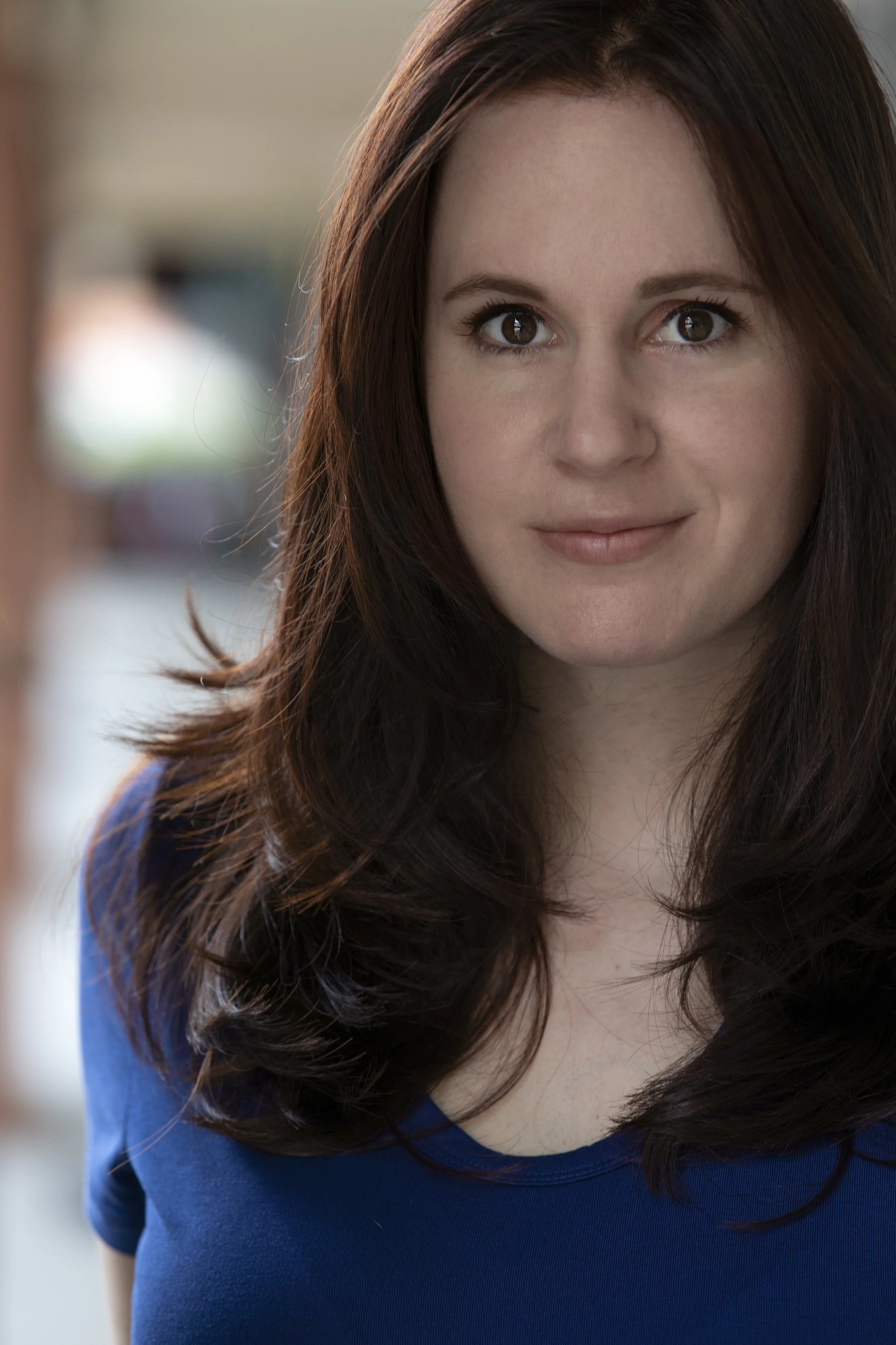 Headshot of woman with medium-length brown hair, wearing a blue shirt, and smiling softly.