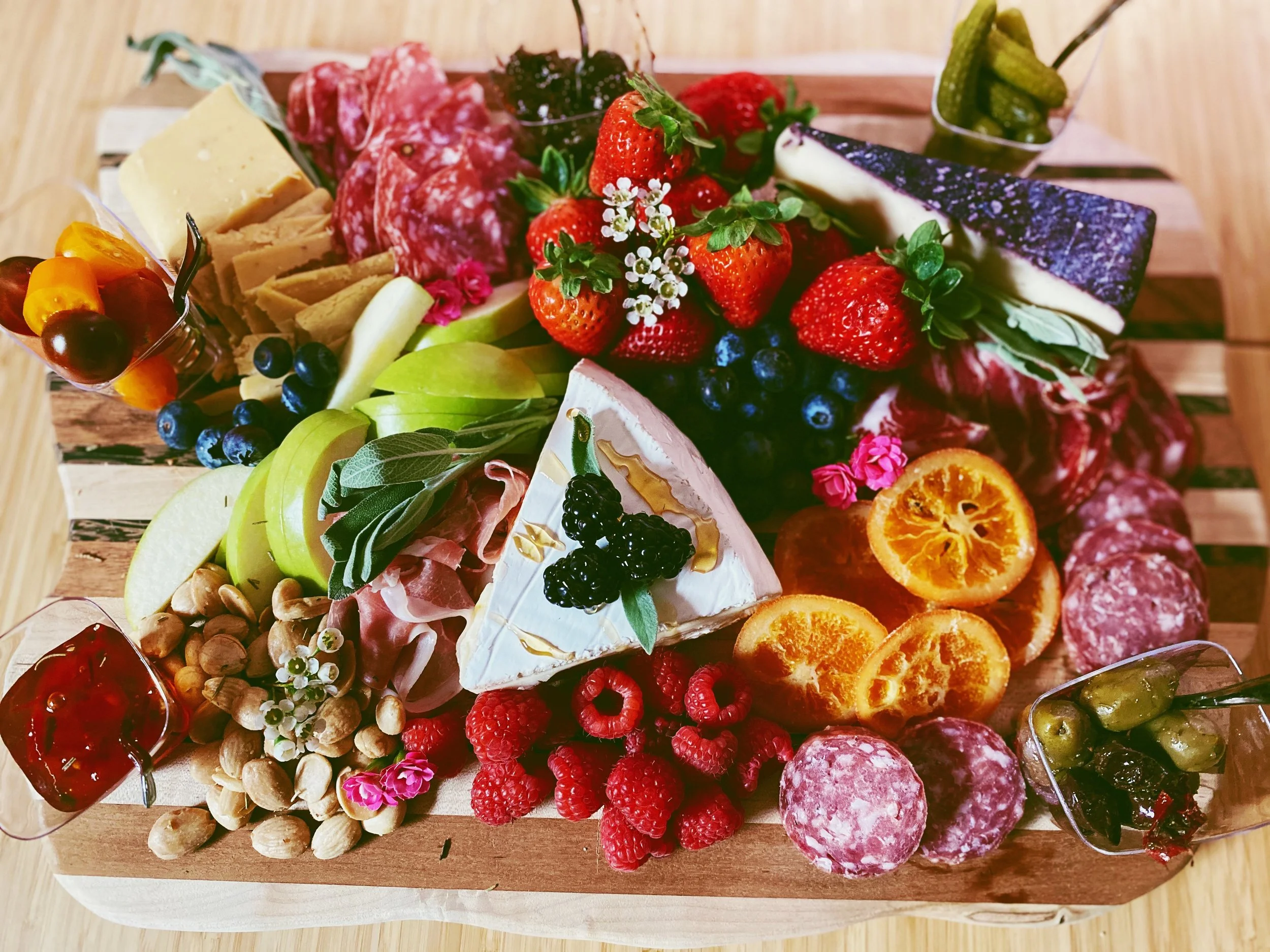 Charcuterie board with assorted cheeses, meats, fruits, nuts, and condiments on a wooden platter.