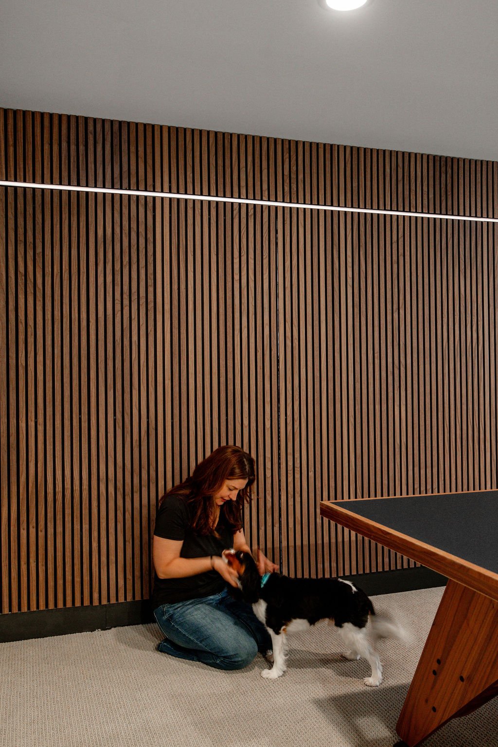 The hidden door has been closed and Rachel is crouched down on the ground and petting Bernie. 