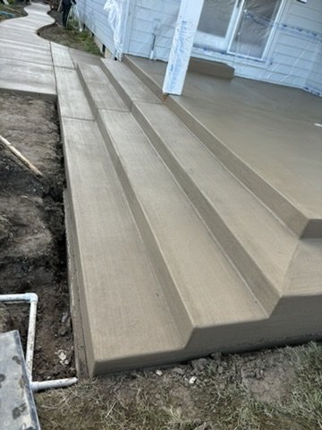 Freshly poured concrete steps and porch with adjoining sidewalk