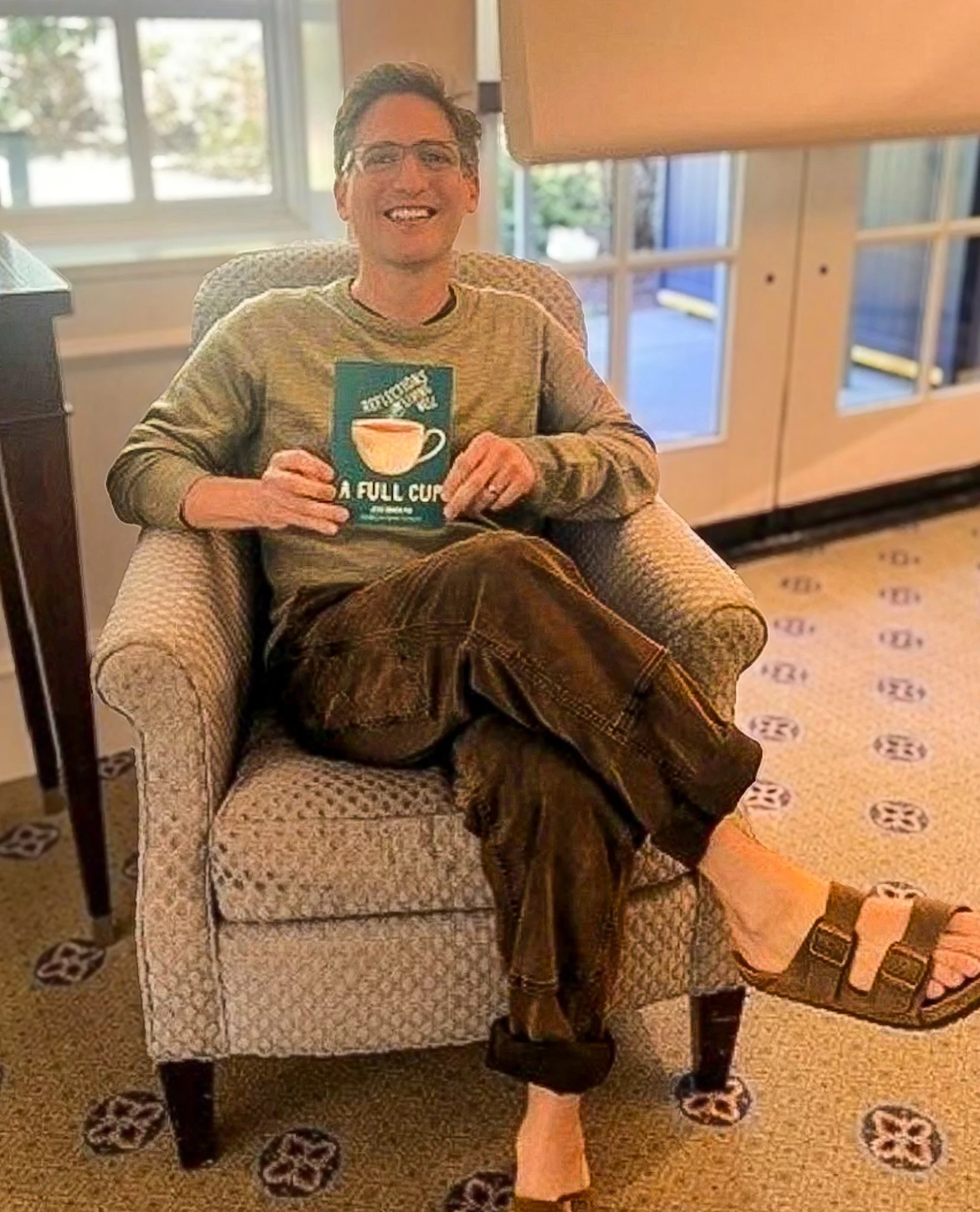 Jesse Erdheim smiling and holding a copy of A FULL CUP: Reflections on Living Well.