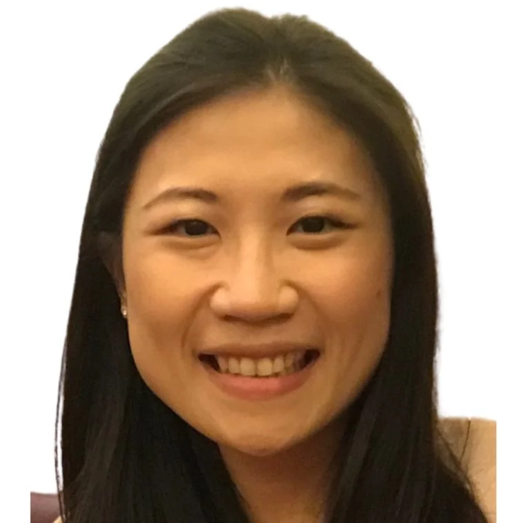 A young woman smiling with long dark hair and wearing small earrings.