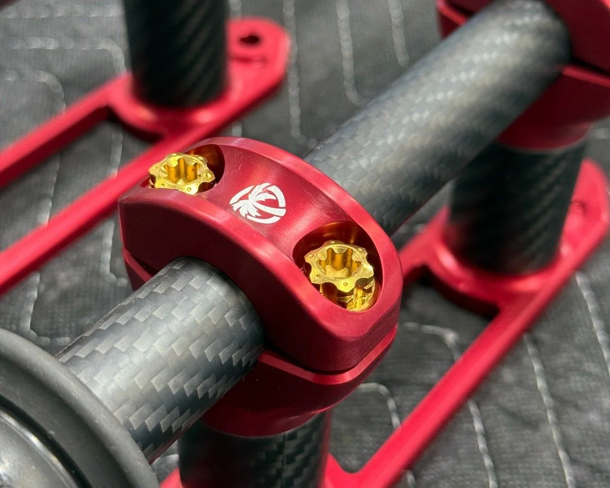 Carbon-fiber tube assembly with red machined clamps and gold fasteners at Papadakis Engineering.