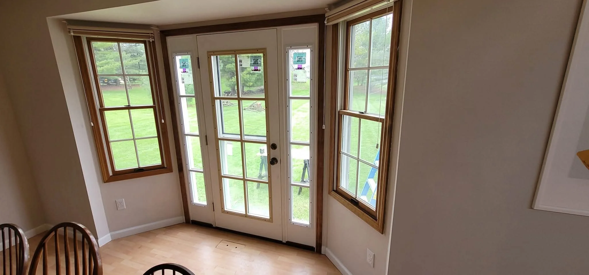 View of a kitchen area with a glass-paneled door and windows, overlooking a green yard.
