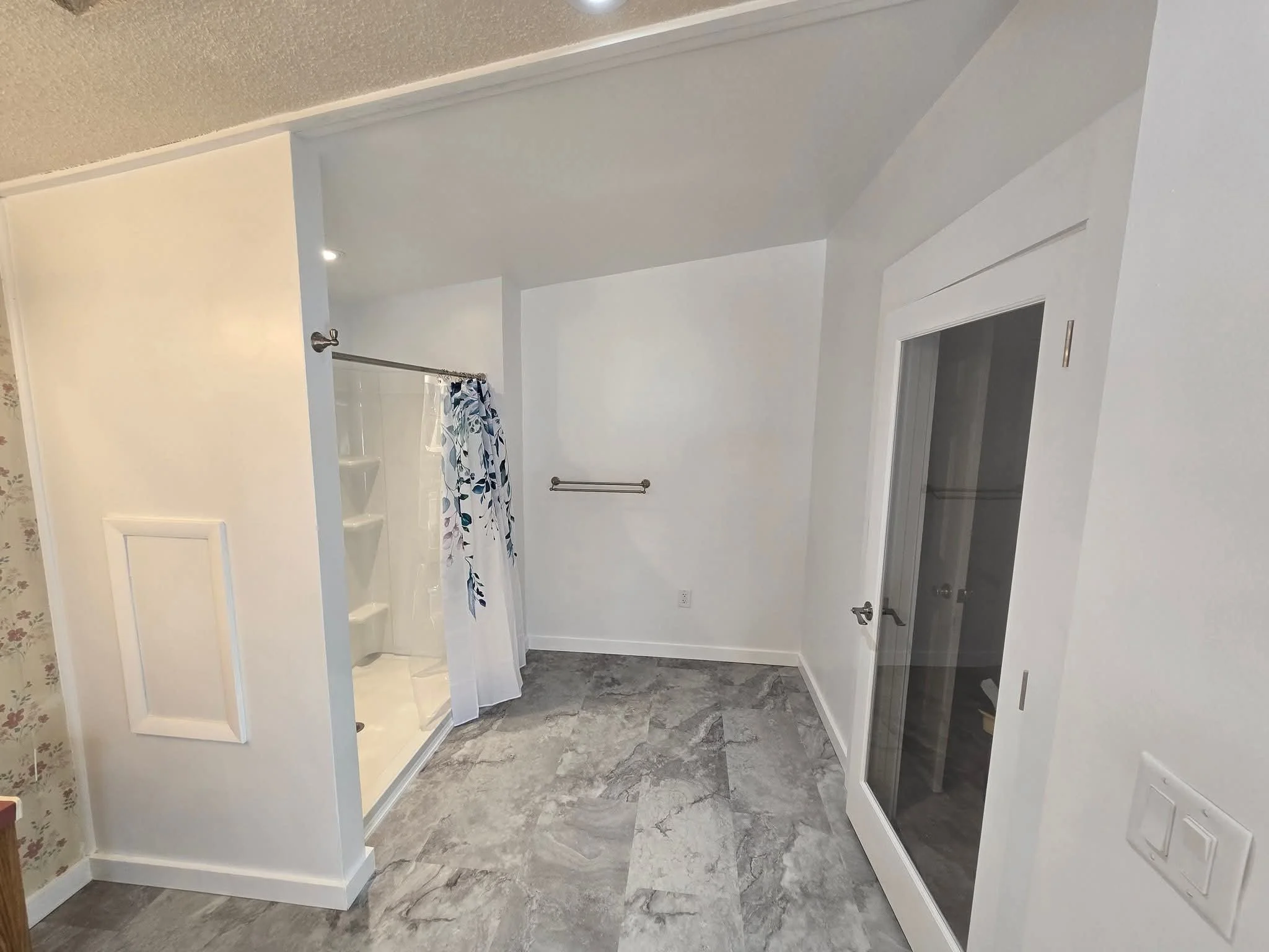Empty bathroom with shower stall, glass door, and white walls.