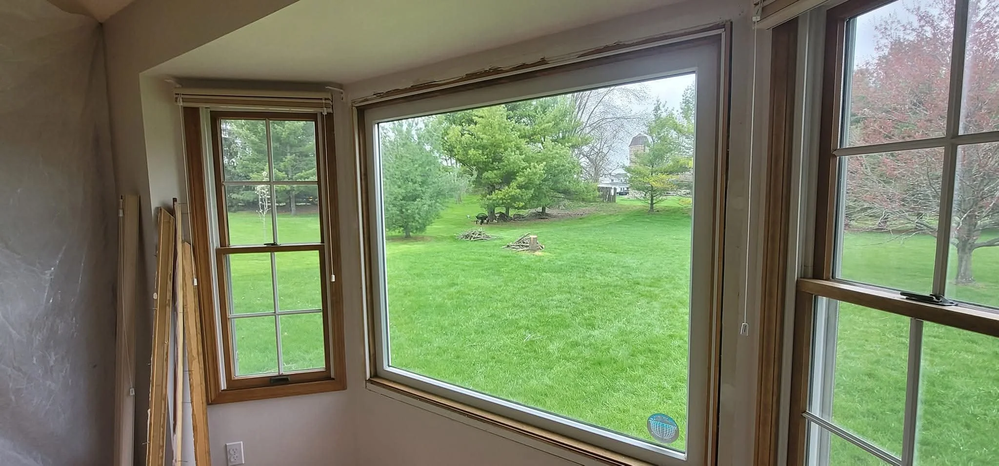 Room with large window showing a grassy backyard with trees and a chimney in the distance