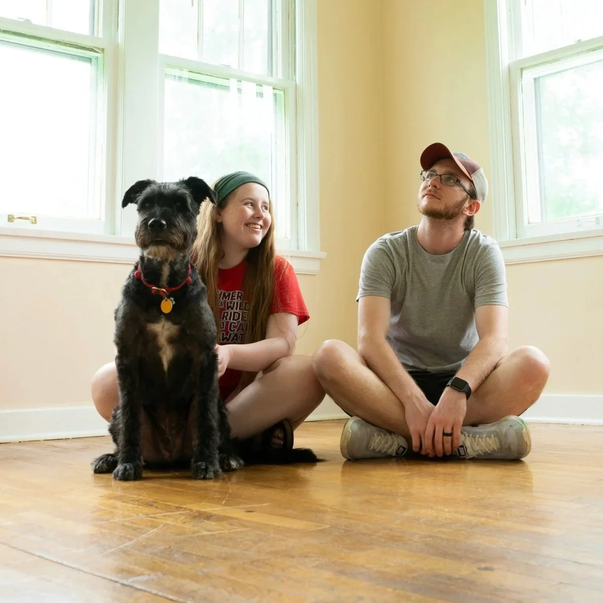 Two people and a dog sitting in an empty home.