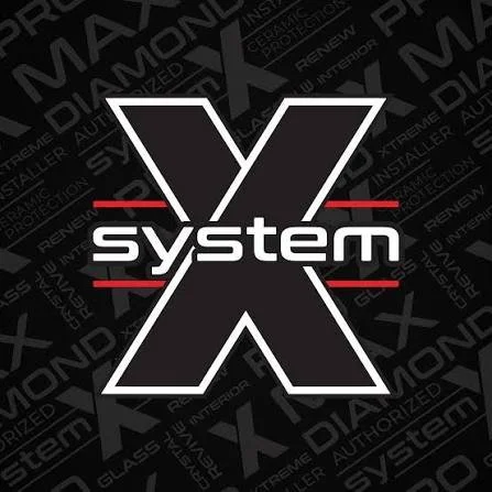 Graphic design of a logo with a large black 'X' outlined in white, the word 'system' in lowercase white letters across the center, and red horizontal lines above and below the word. The background has various technical and automotive-related words and phrases in a dark pattern.