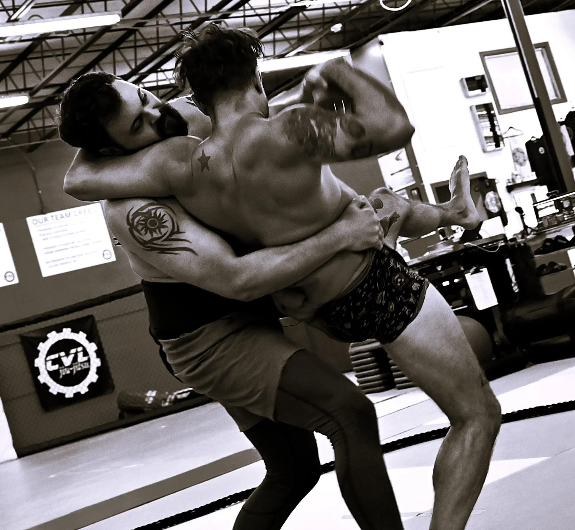Two women punch each other during a boxing or MMA match in an indoor gym, with a referee or coach watching close by.